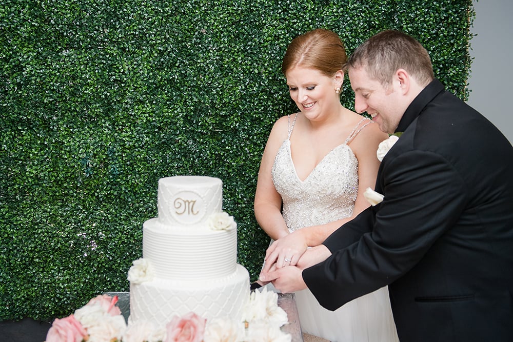 cake cutting with ivy wall background, wedding photography at ballroom reception