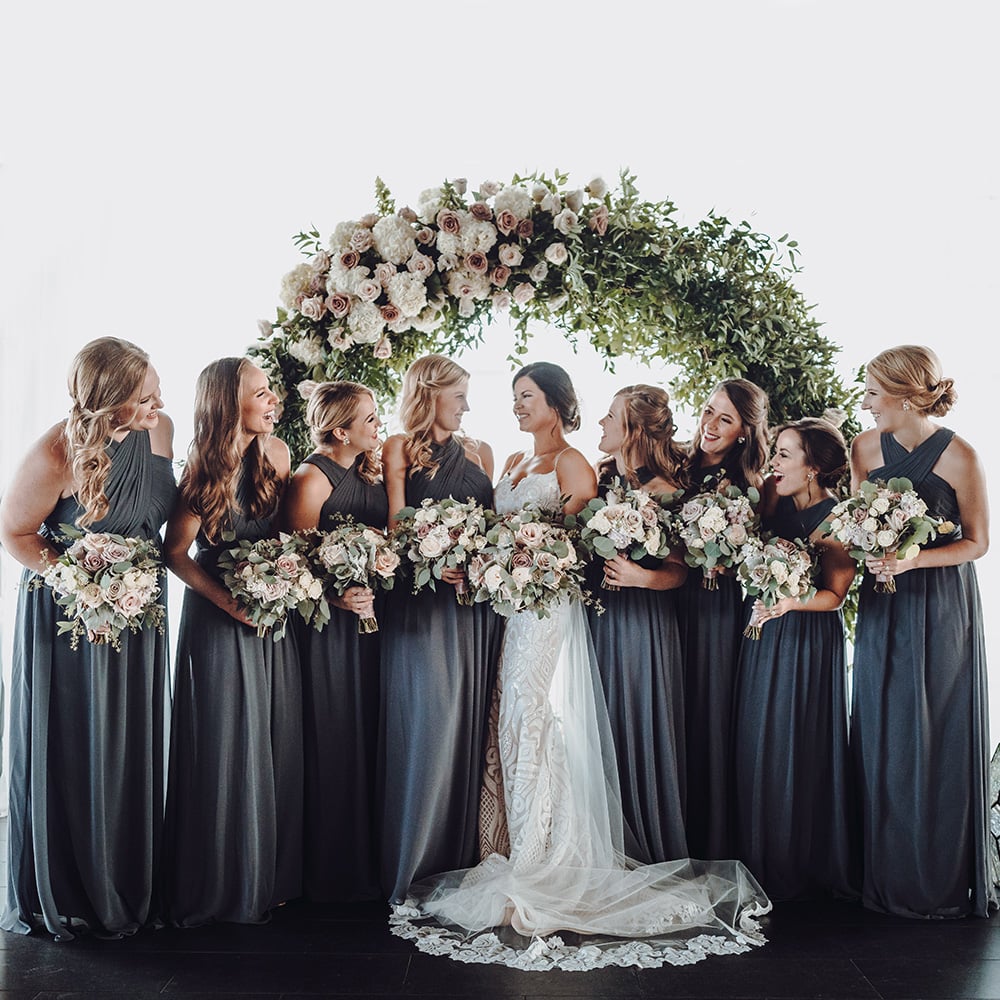 bridesmaids with bouquets in front of floral hoop