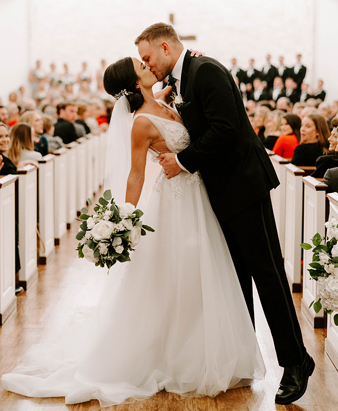 Bride and groom kiss at the end of the ceremony aisle at wedding venue, Briscoe Manor in Houston, TX.