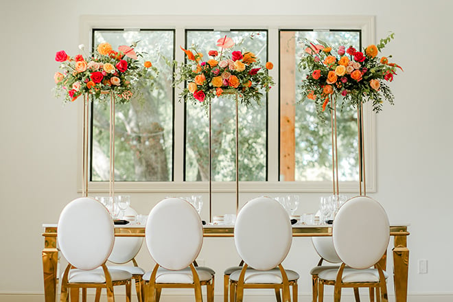 Dining table with tall citrus hued floral centerpieces 