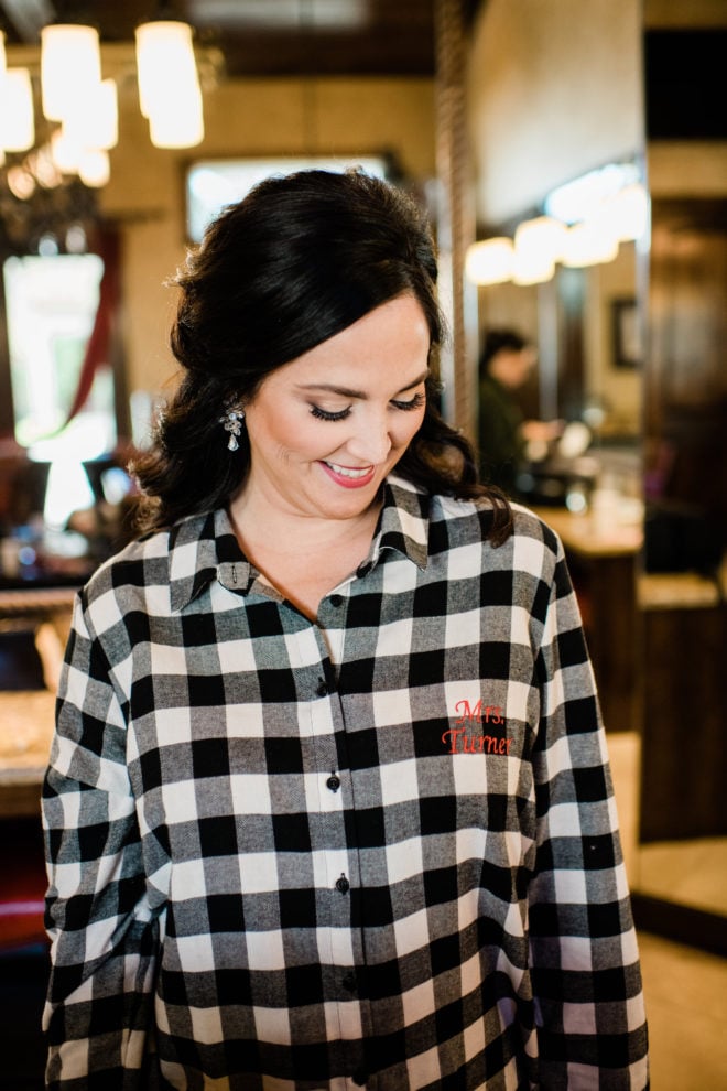 Bride getting ready in personalized plaid shirt for wedding. 