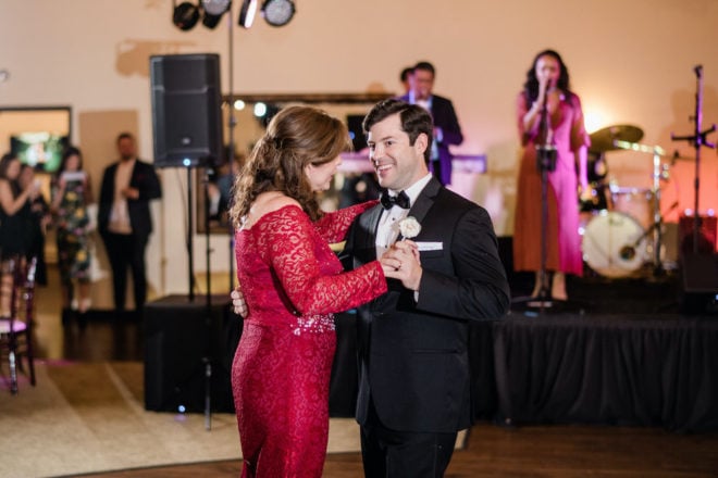 Mother and son dance at wedding in front of a live band. 