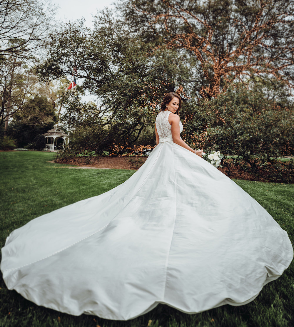 Bride shows off the back of her wedding gown showcasing the impressive train and lace back details.