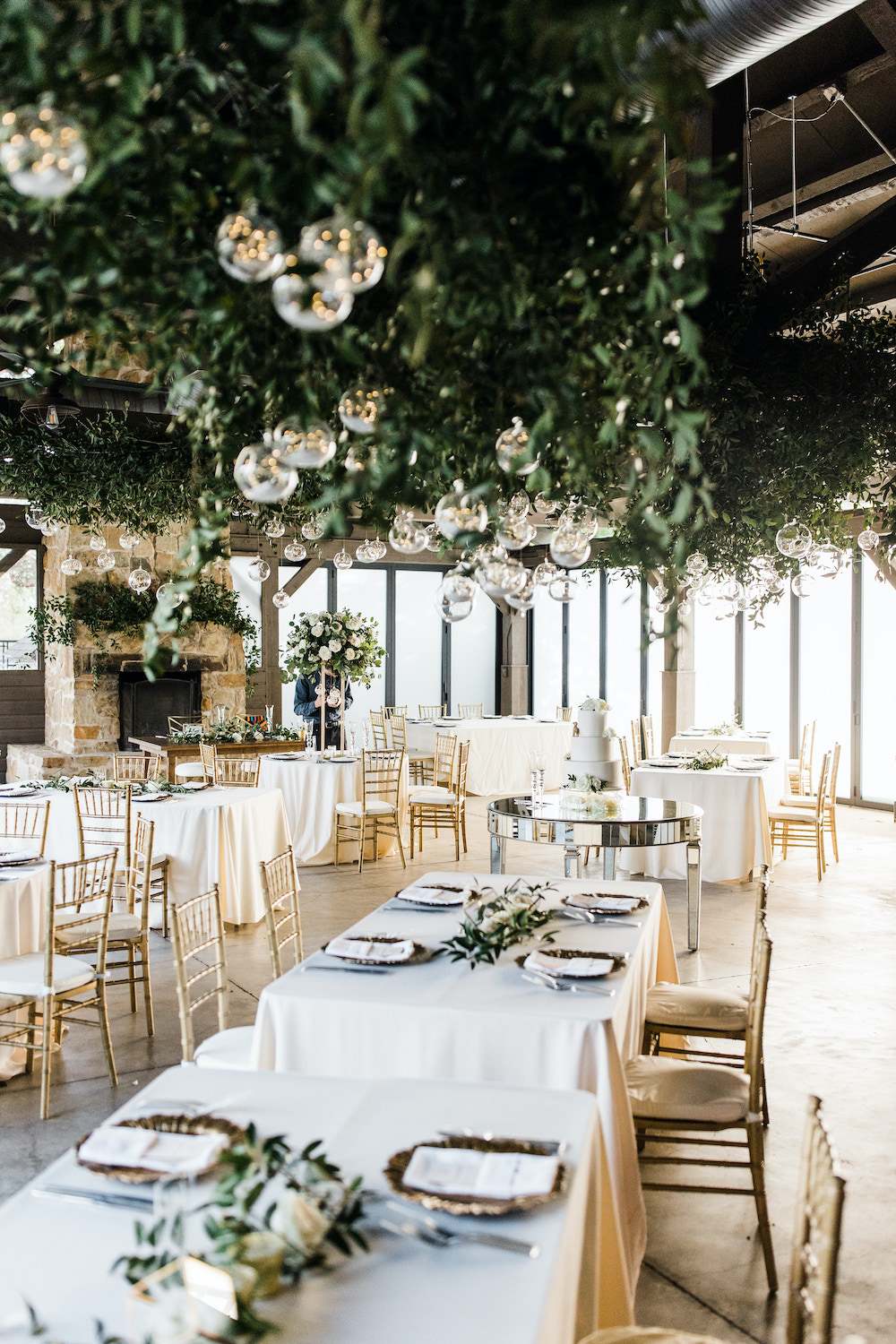 Gorgeous white and gold garden reception at the Hyatt Regency Lost Pines with greenery hanging from the ceilings with glass globes filled with twinkling lights. 