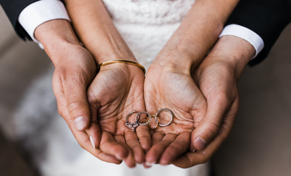 Bride and grooms hands pictured holding their stunning engagement and wedding bands. 