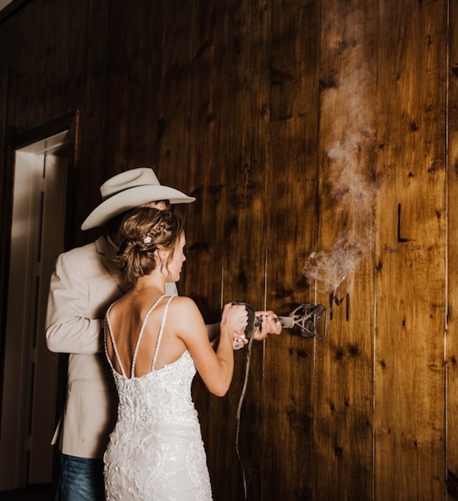 Couple branding their initials into the wall on farm to celebrate their marriage. 