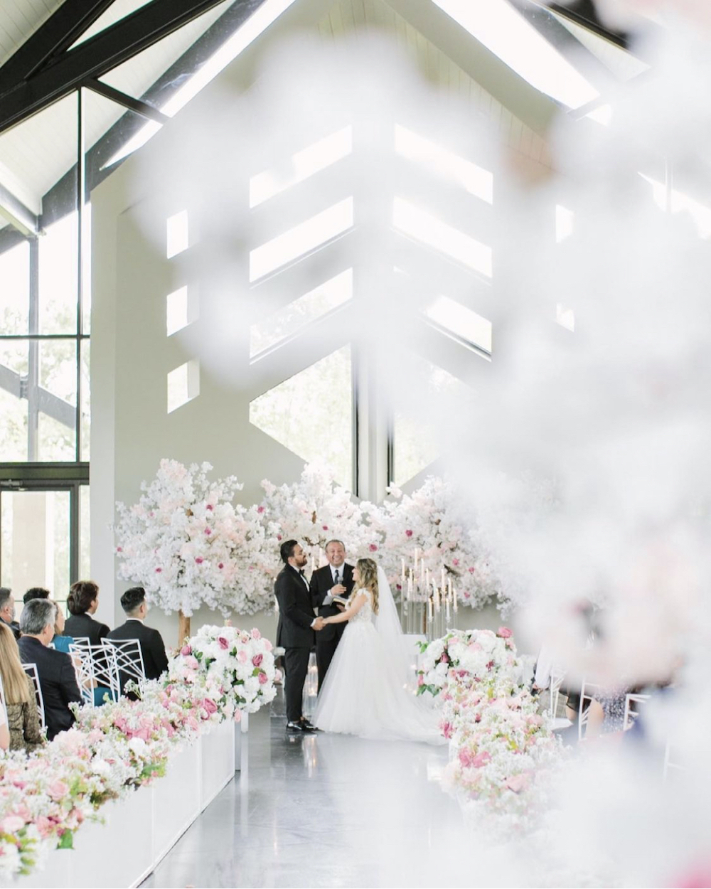 Interior shot of ceremony with lush pink and white florals by event designer, Mod Effect Events.