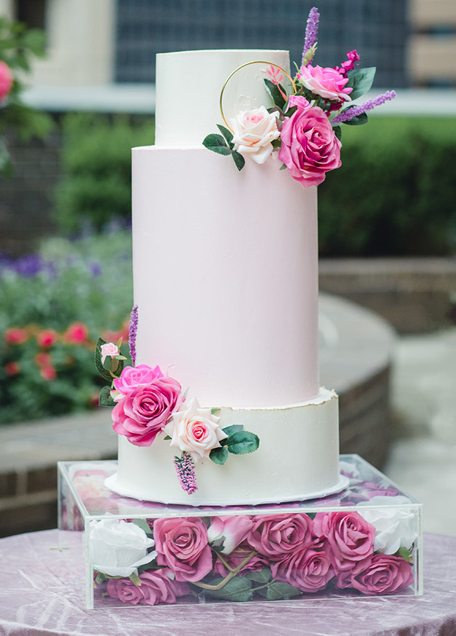 A three-tiered wedding cake features layers of various heights and floral accents. 