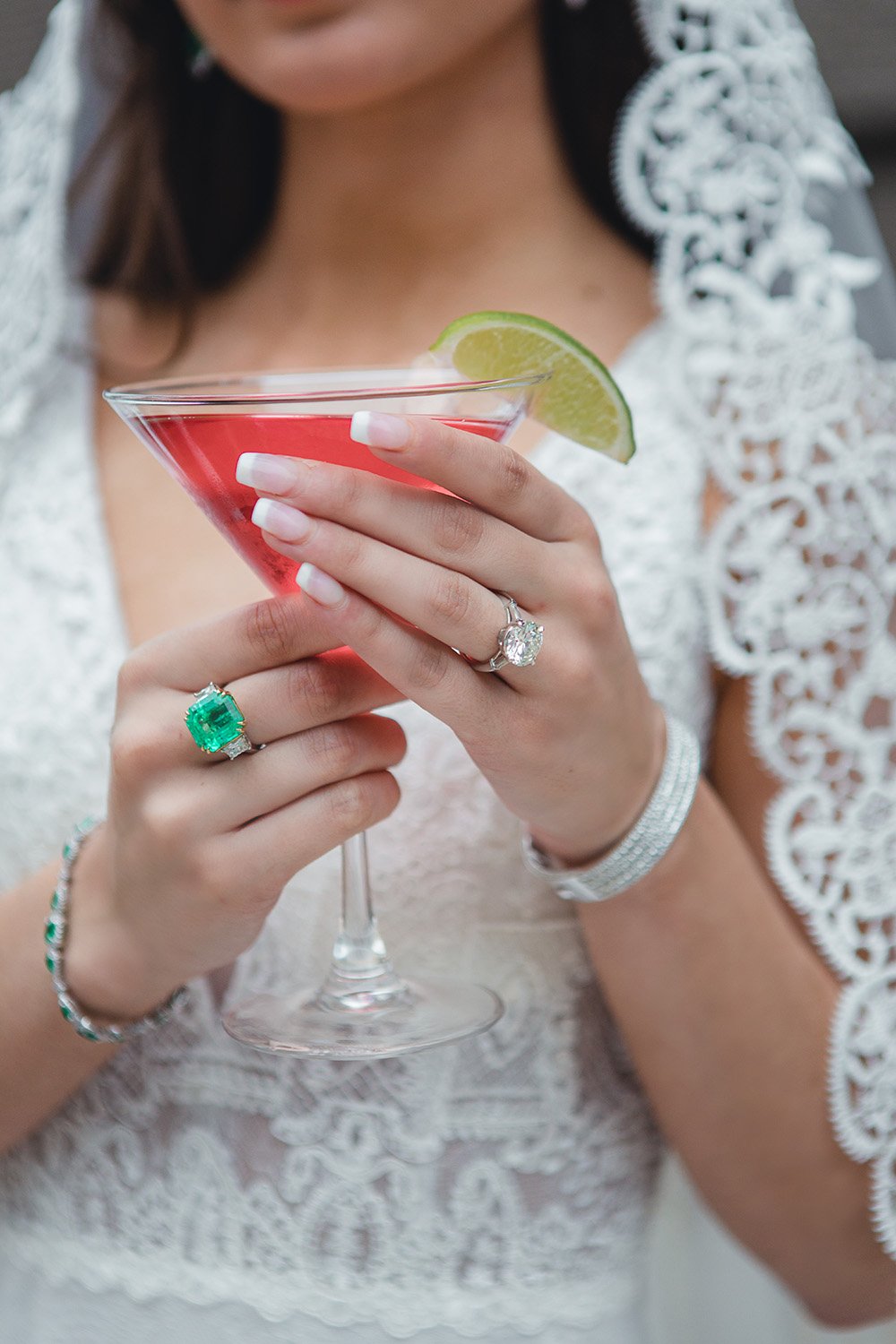 Our bride dons her gorgeous emerald and diamond wedding jewelry while holding a pink cocktail with a lime sliver.