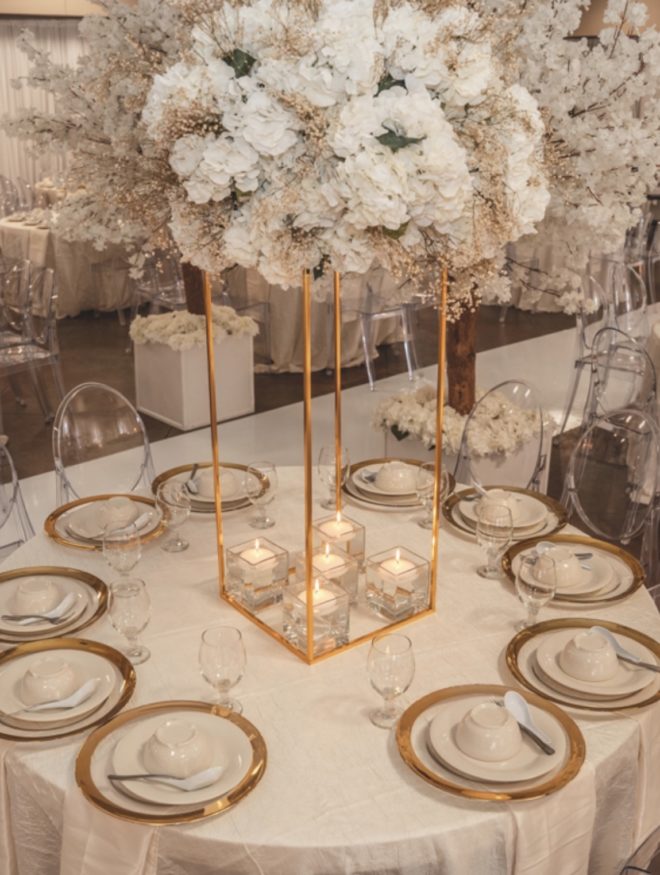 Wedding guest table decorated in gold and ivory placesettings with lush blooming floral centerpiece with beige, white and ivory florals by Mod Effect Events 