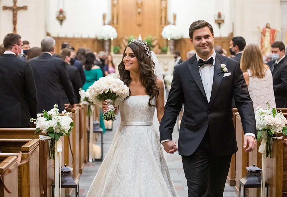 Bride and groom walk down the aisle together at their ceremony in a chapel. 