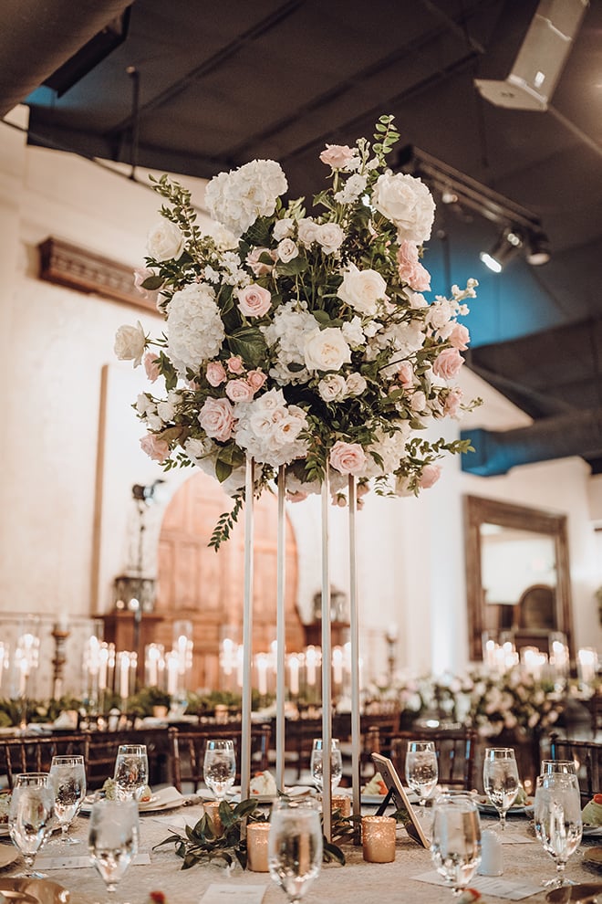 A reception table with a towering white and blush floral arrangement.