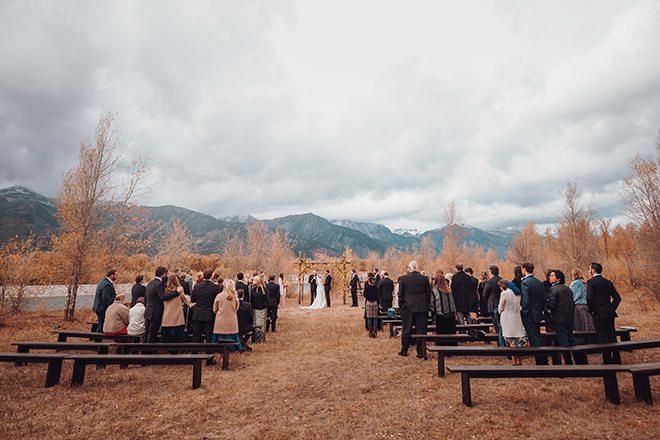 Jackson Hole, Wyoming Outdoor wedding with bride and groom under an altar of aspens aside Snake River with the Grand Tetons in the background.