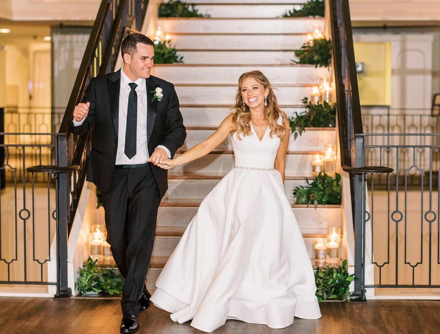 Bride and Groom hold hands smiling as they leave the wedding.