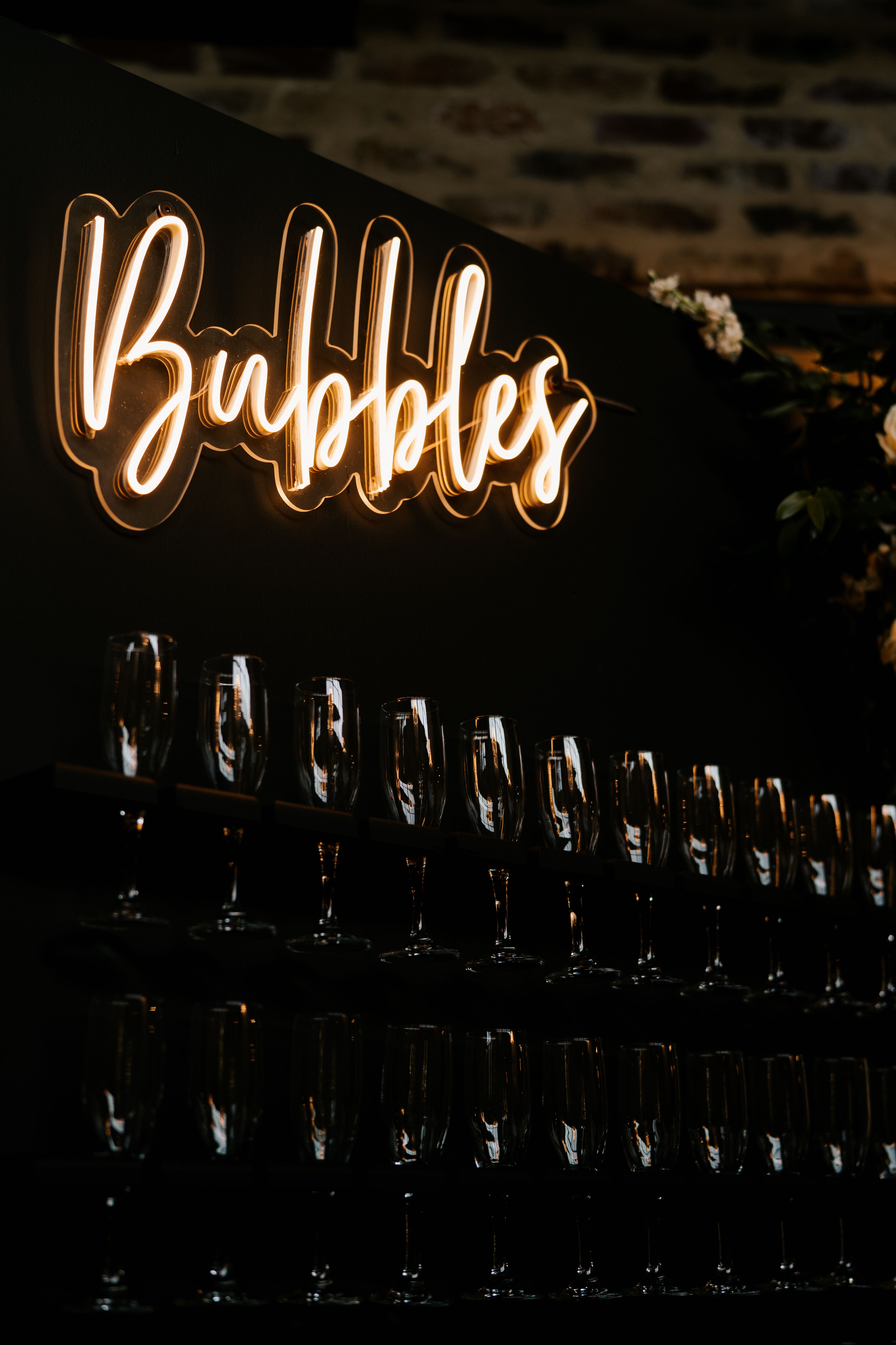 A champagne wall is illuminated by the neon bubbles sign at this industrial chic wedding.