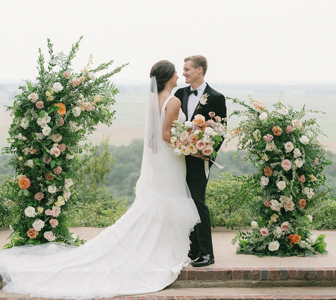 Bride and groom stand at the alter for their artfully curated Southern wedding. Bride is holding her bridal bouquet and there is a beautiful view of the hill country.