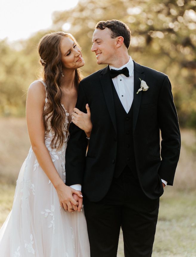 Bride and groom gaze into each other's eyes while holding hands with trees and grass behind them after their wedding ceremony in Spring Branch, Texas.