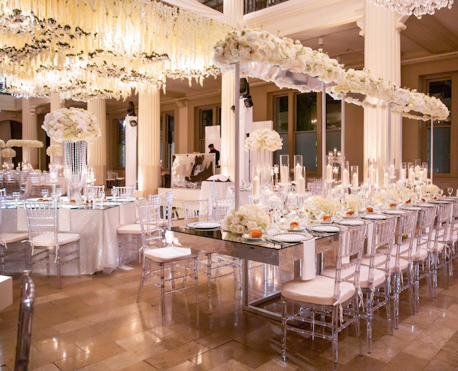 Reception set up and decor in white lush florals, hanging florals, and warm lighting. 