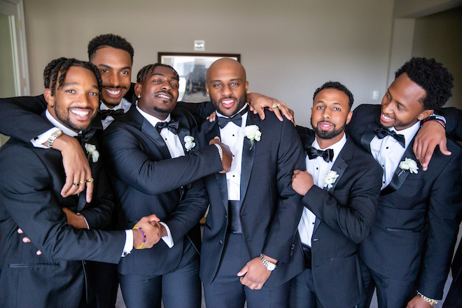 Groom and groomsmen embrace each other in a lounge at the Corinthian Houston. 