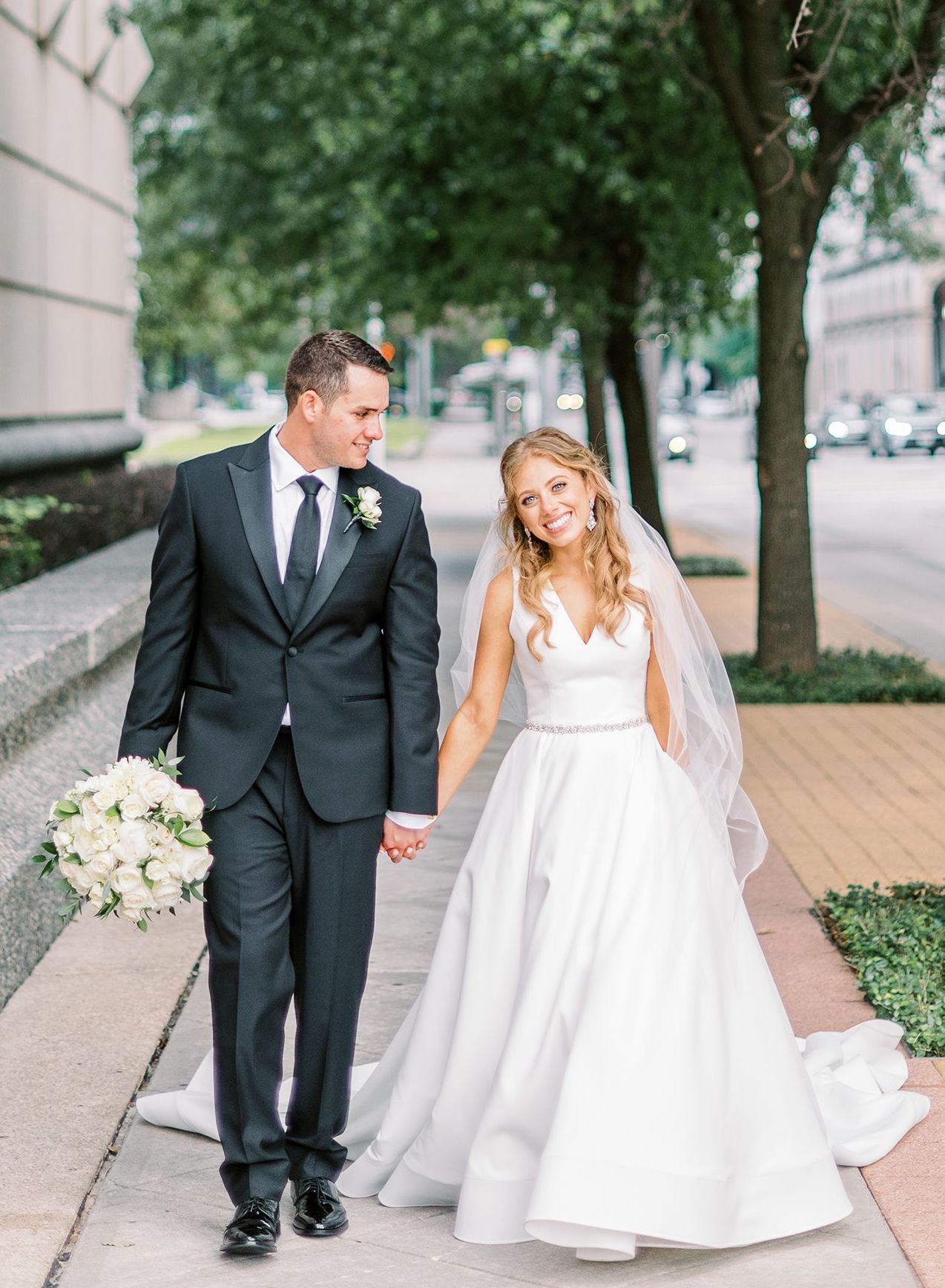Bride and groom holding hands and walking in Downtown Houston.