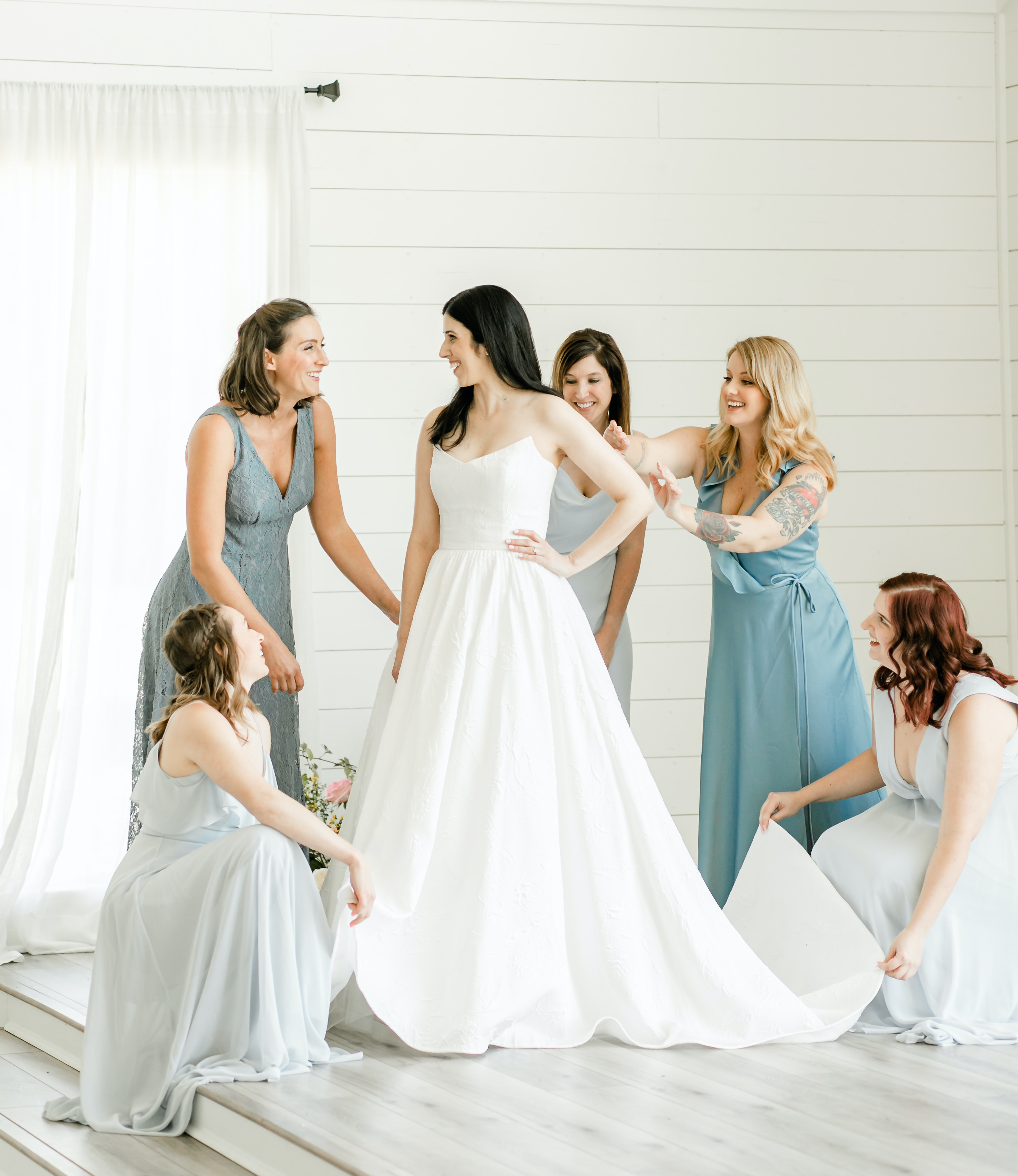 The bride gets ready with her bridesmaids, who are in different shades of blue dresses.