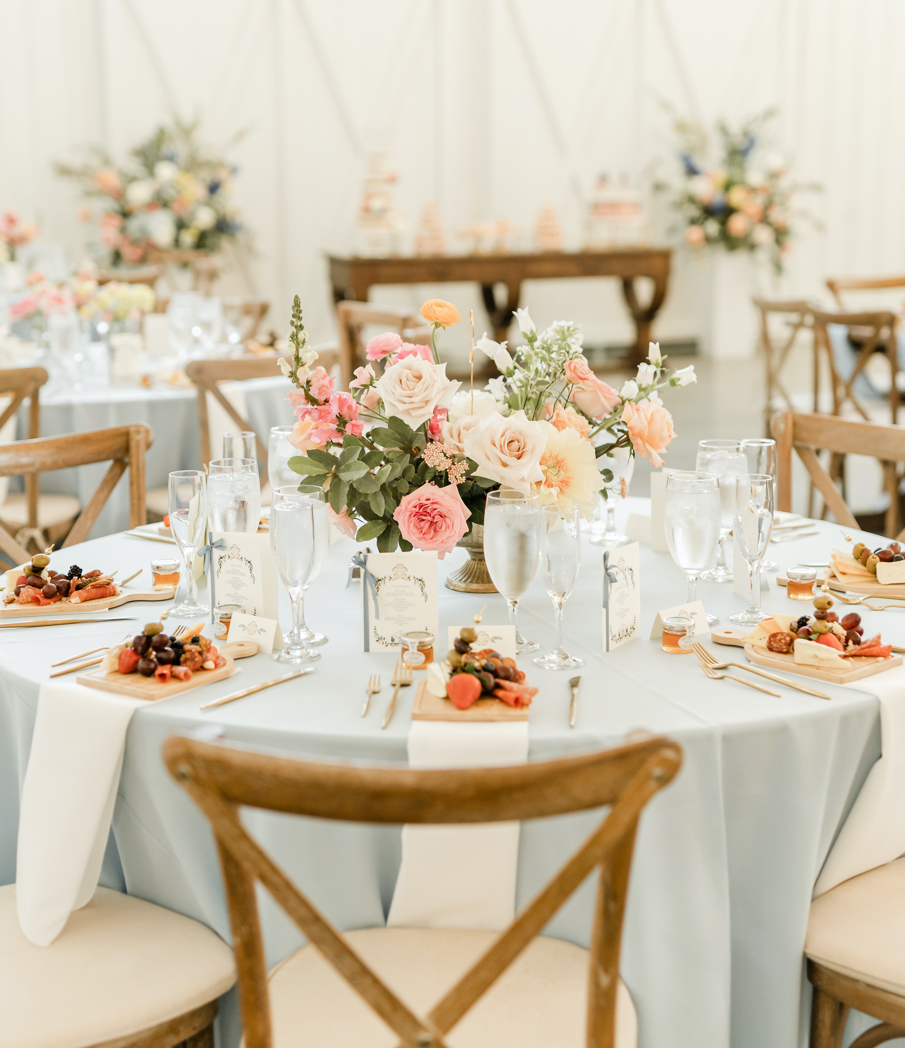 The reception tables are set with a light blue table cloth and a charcuterie board is placed at each guests seat, who are close friends of the bride and groom.