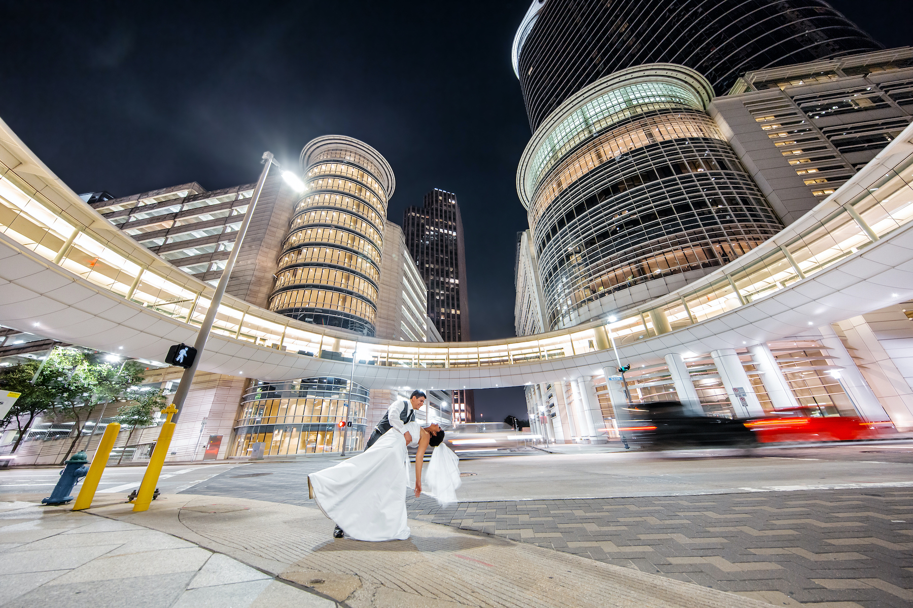 A suited groom dips his white gown bride in front of the downtown venue Whitehall Houston.