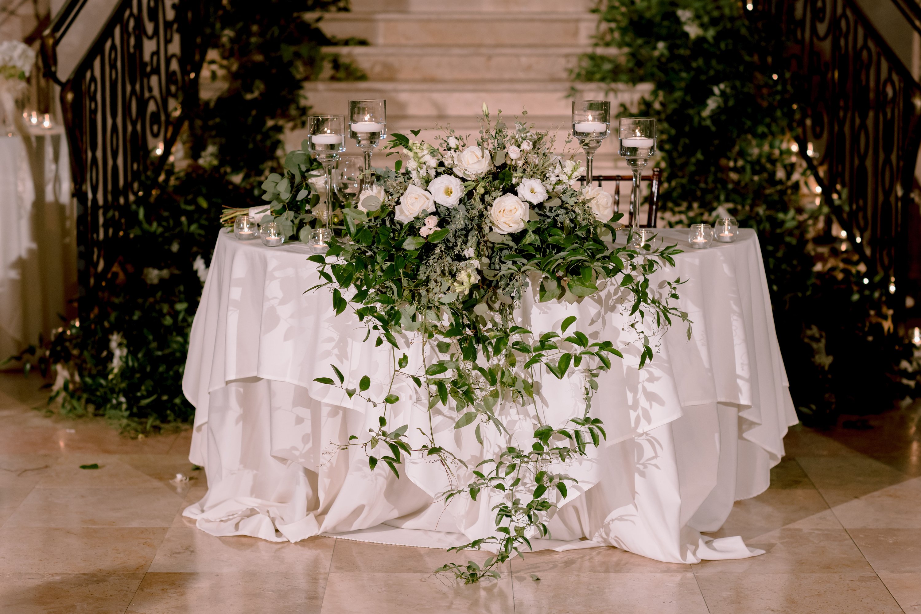 A greenery-filled table next to the grand staircase.