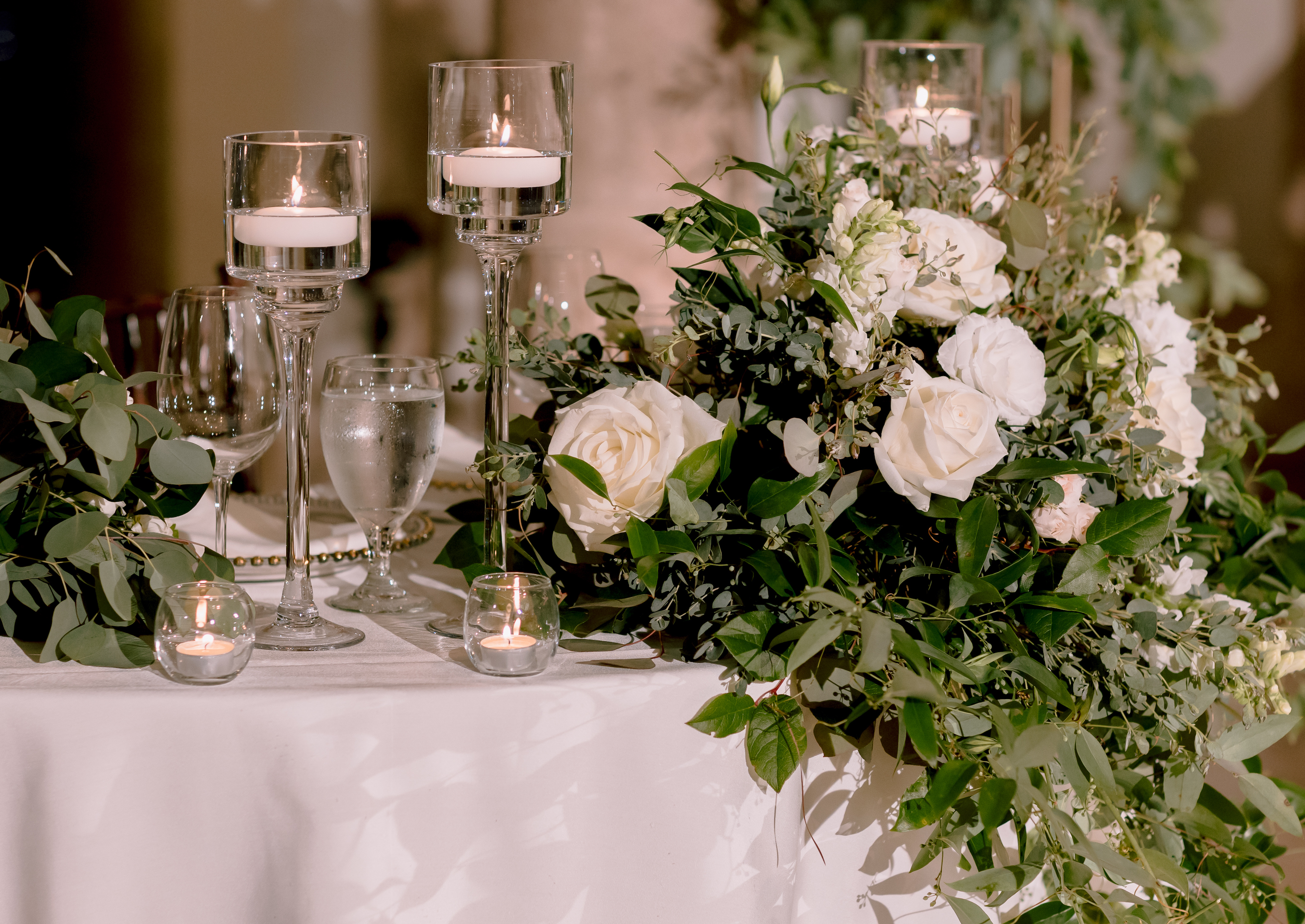 A detail shot of the floating tea lights and greenery with white flowers.