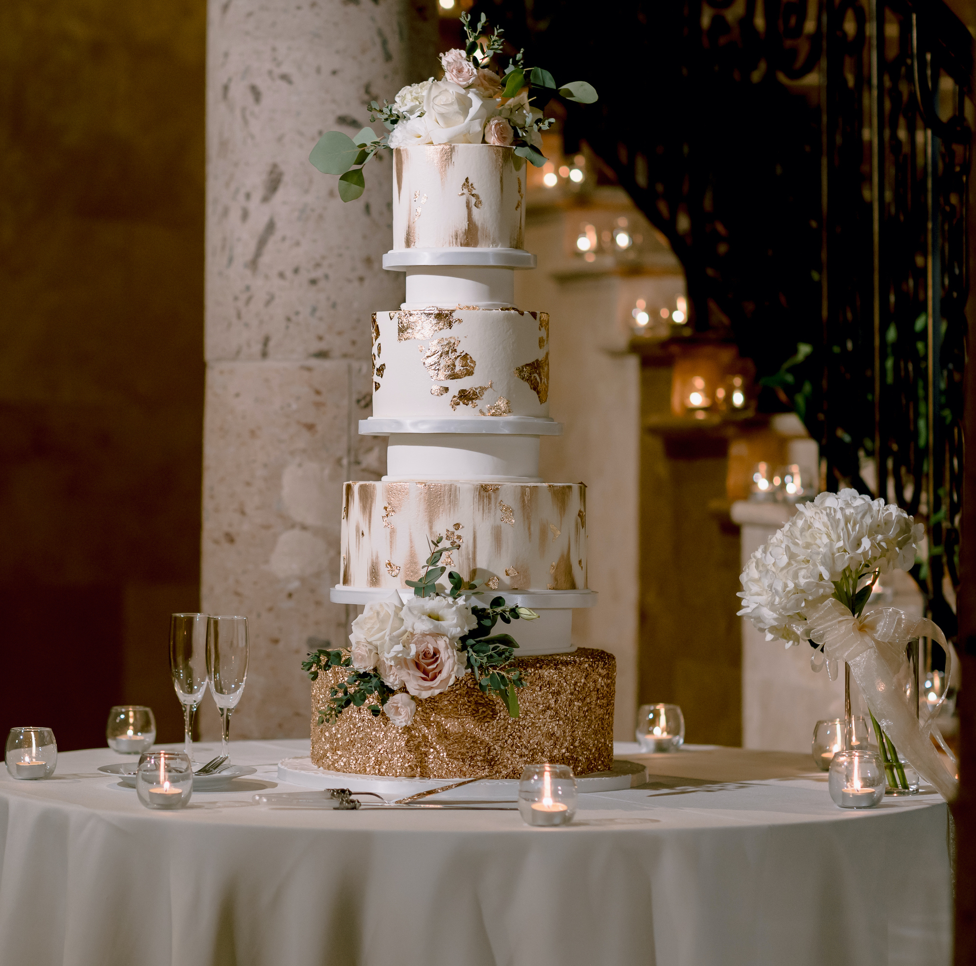 The wedding cake has glittery gold accents and white frosting.