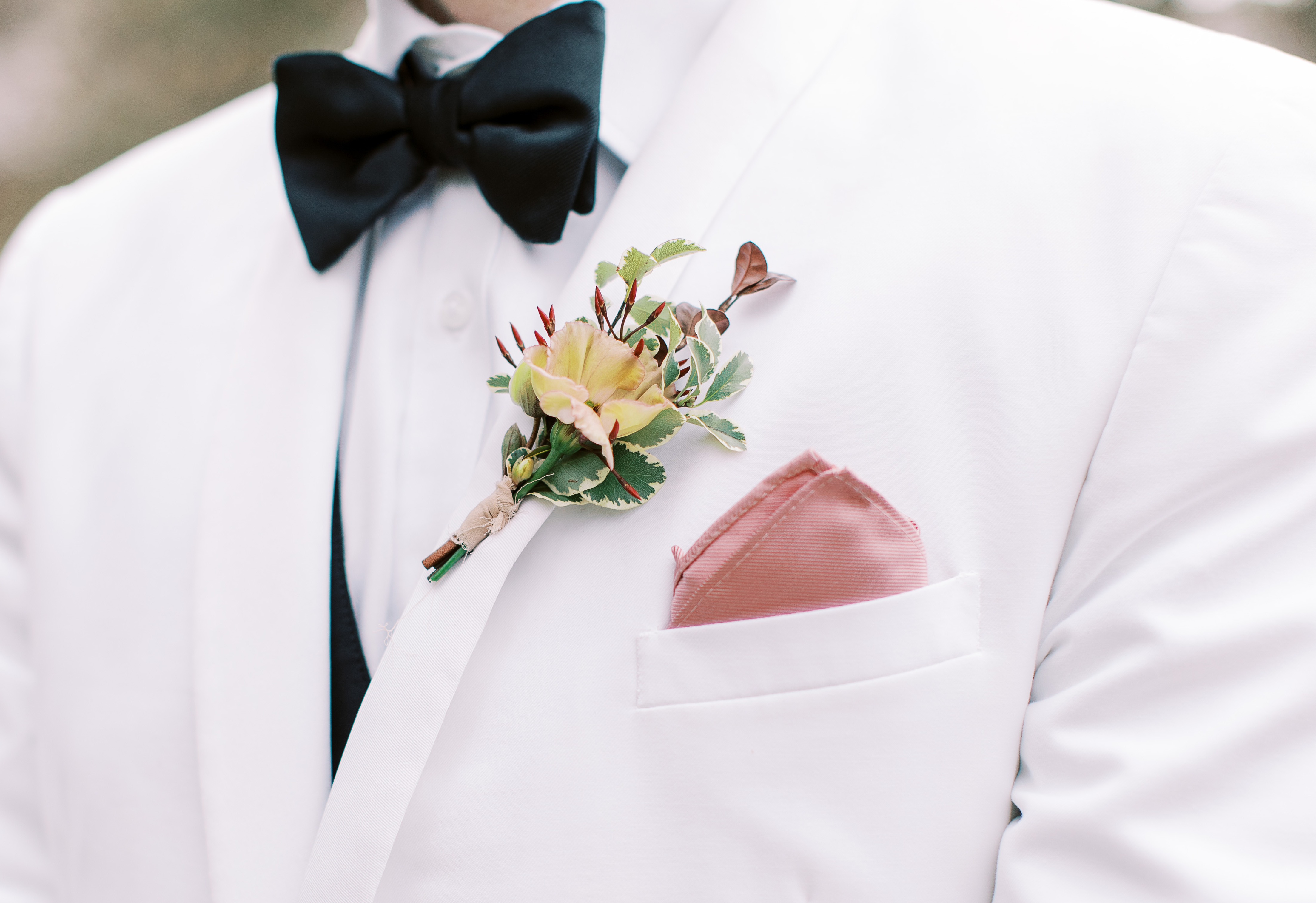 An up close photo of the groom's boutonnière before the al fresco wedding ceremony.