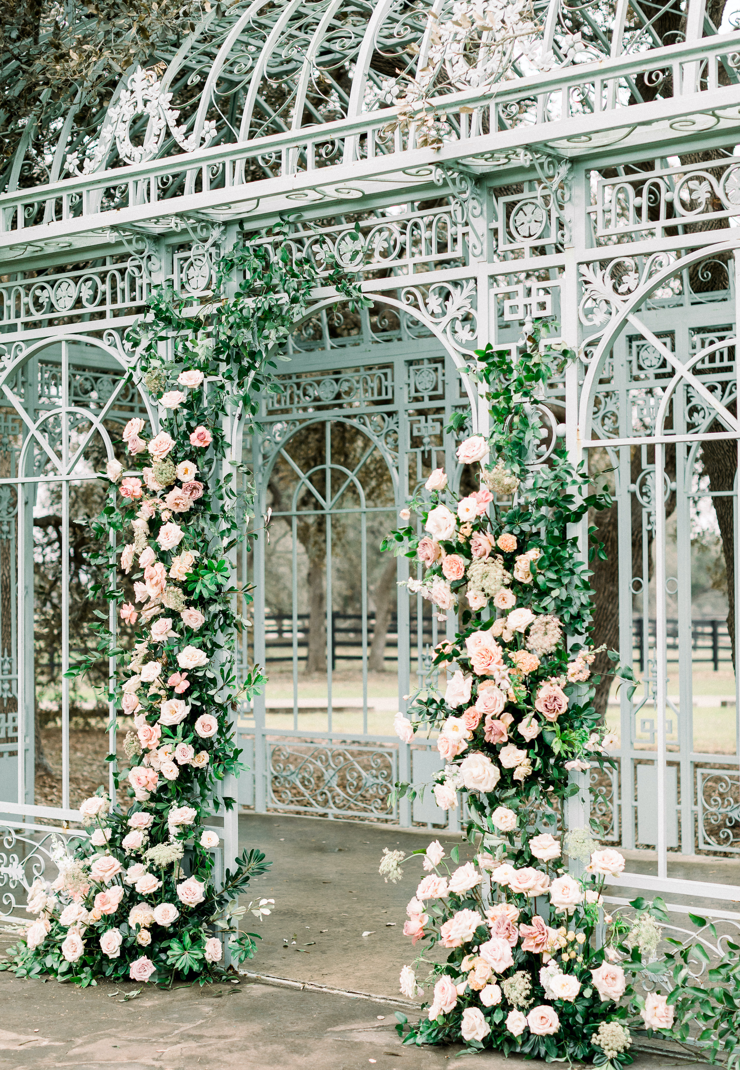 Sage green antique french gazebo decorated with blush garden roses and greenery for an outdoor wedding ceremony in the Texas hill country. 