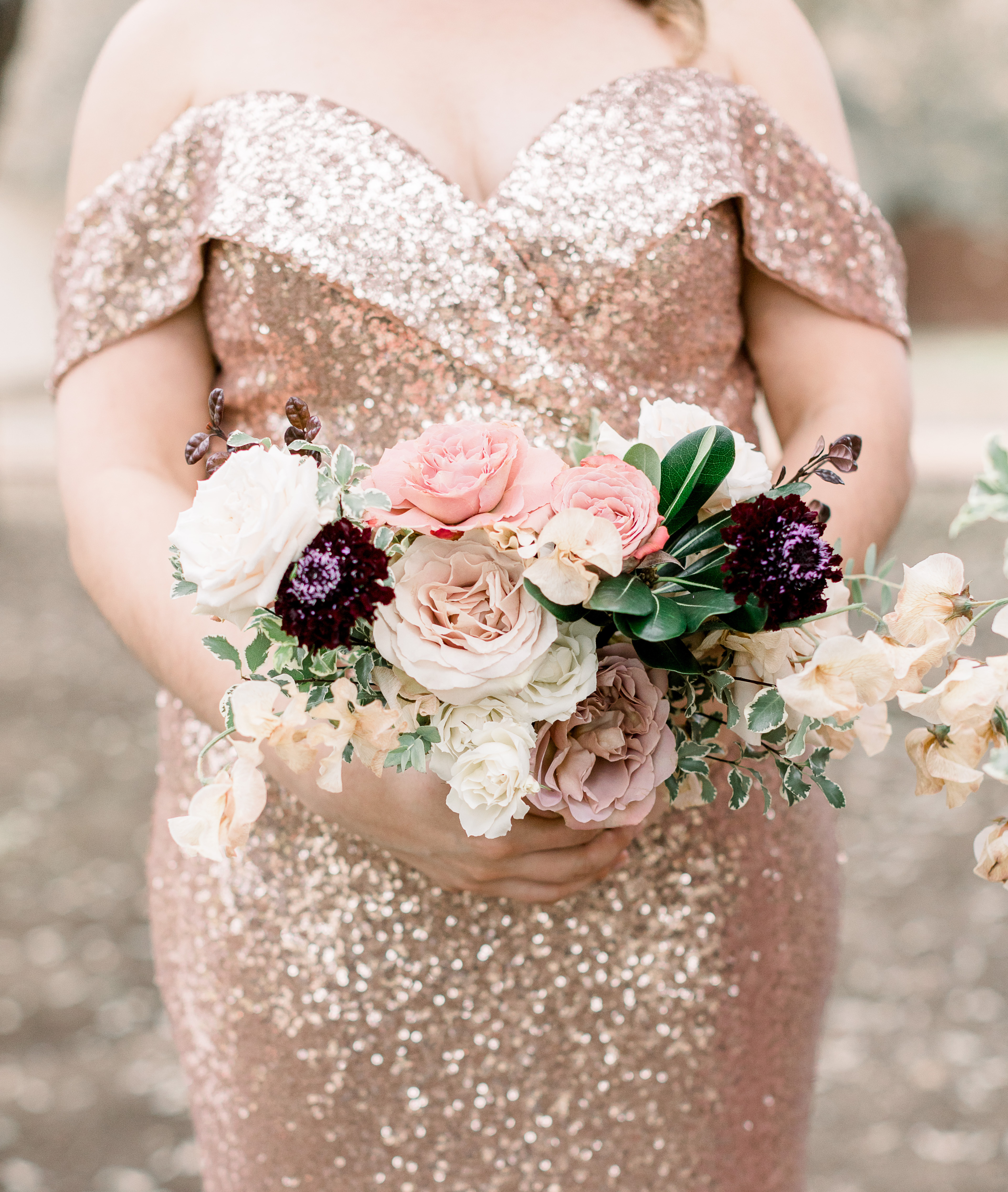 Bridesmaid in an off-the-shoulder rose gold sequin gown holding a blush, purple and ivory floral bouquet at a wedding ceremony in Dripping Springs, Texas. 