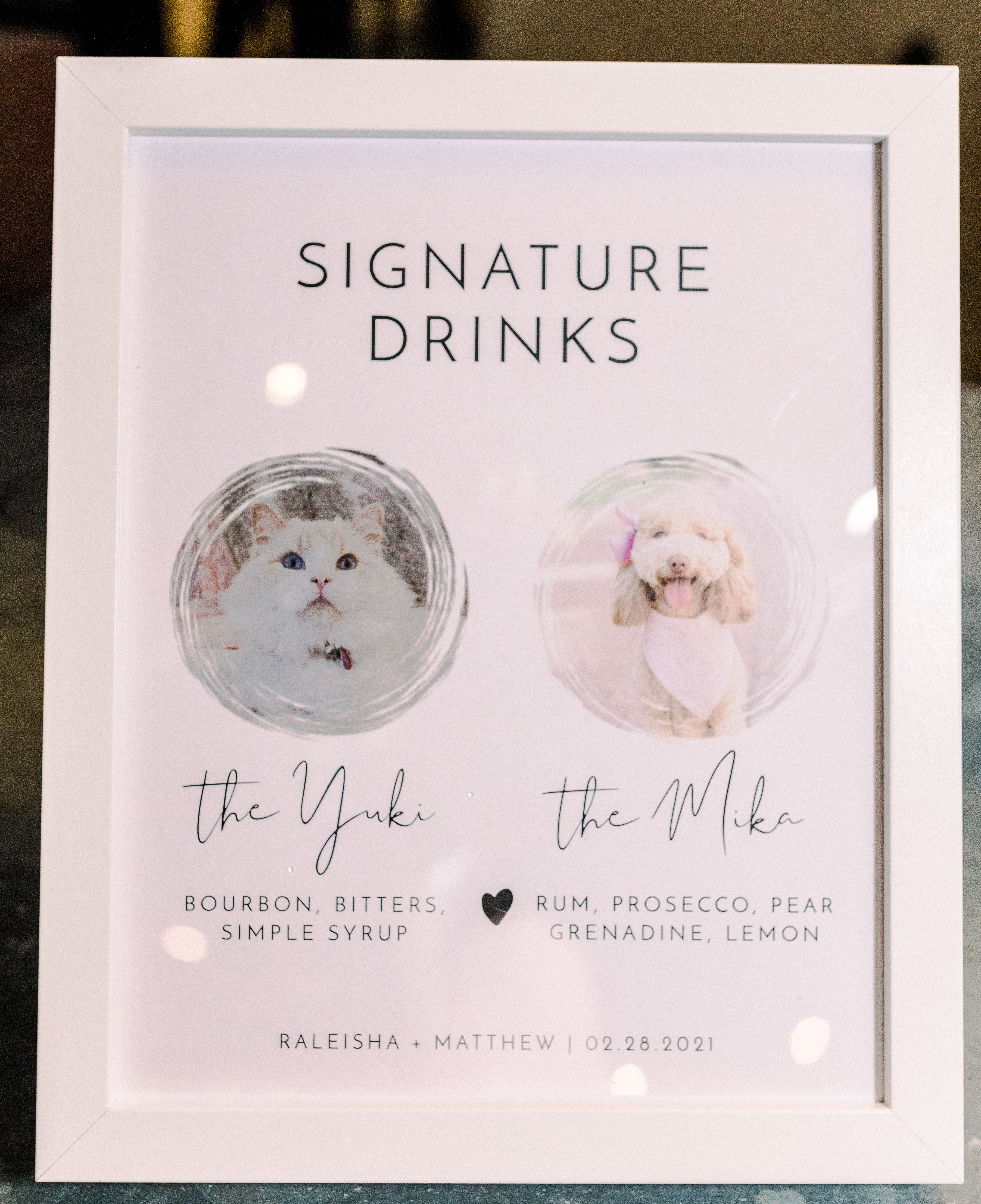 A signature cocktail sign that shows the bride and groom's pets with drinks inspired by them.