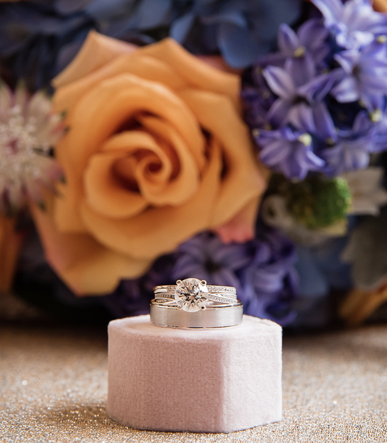 The bride's engagement ring with a background of orange and purple flowers for the whimsical jewel-toned wedding.