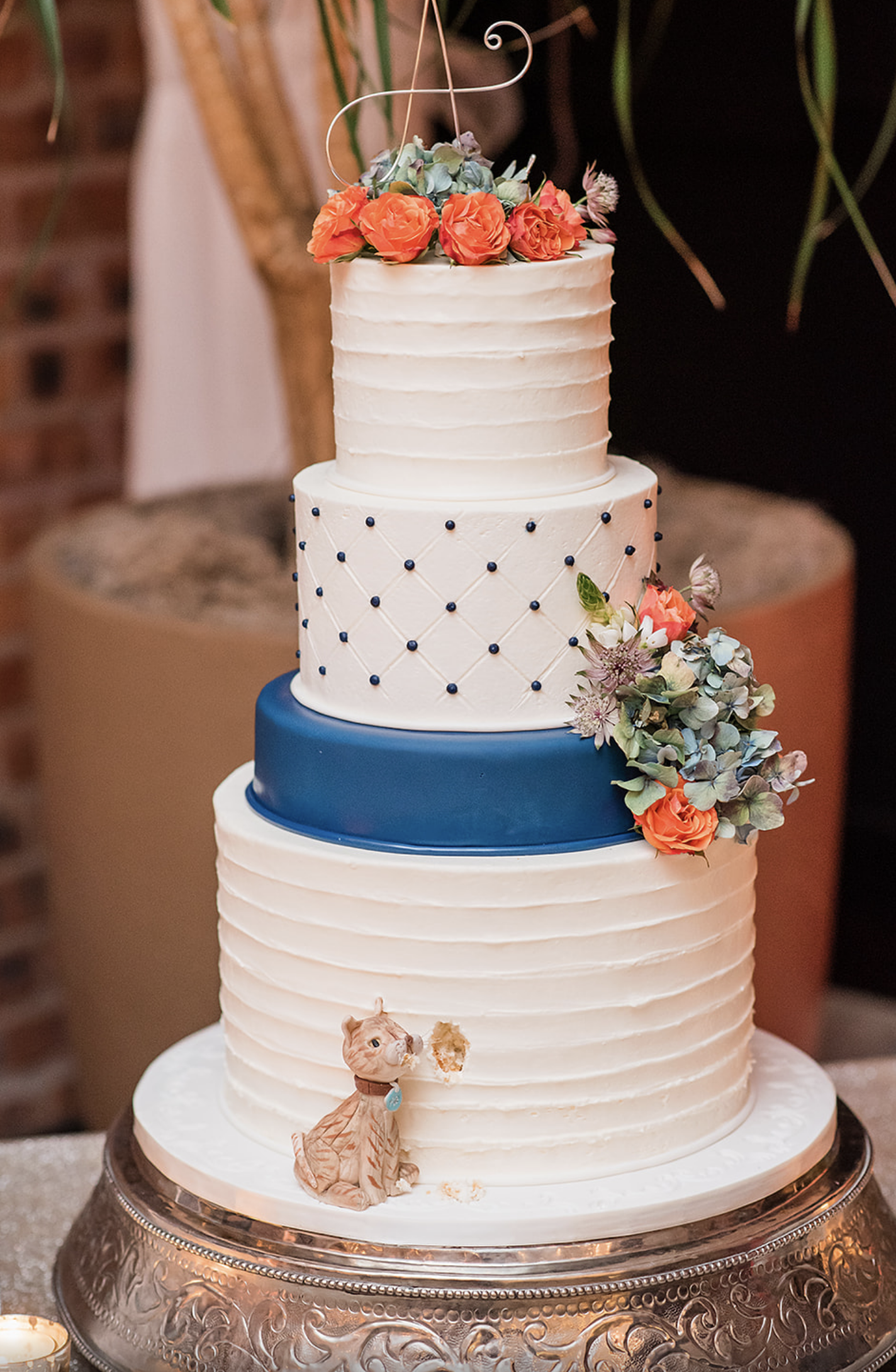 Amy and Jonathan's wedding cake with a mini cat figure placed on the side of it.