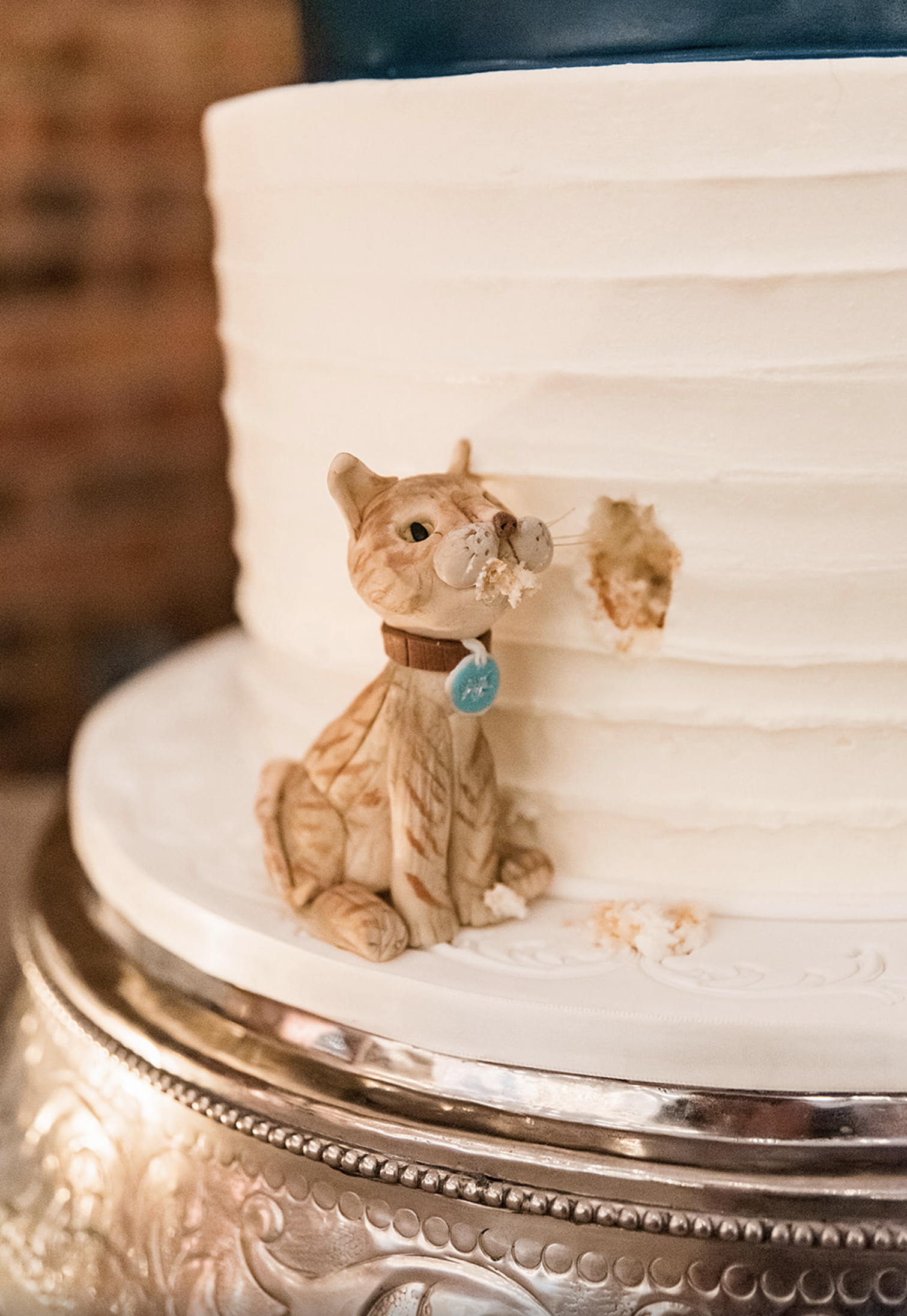 A mini cat figure is placed next to the base of the cake. It looks like the cat is eating some of the cake.