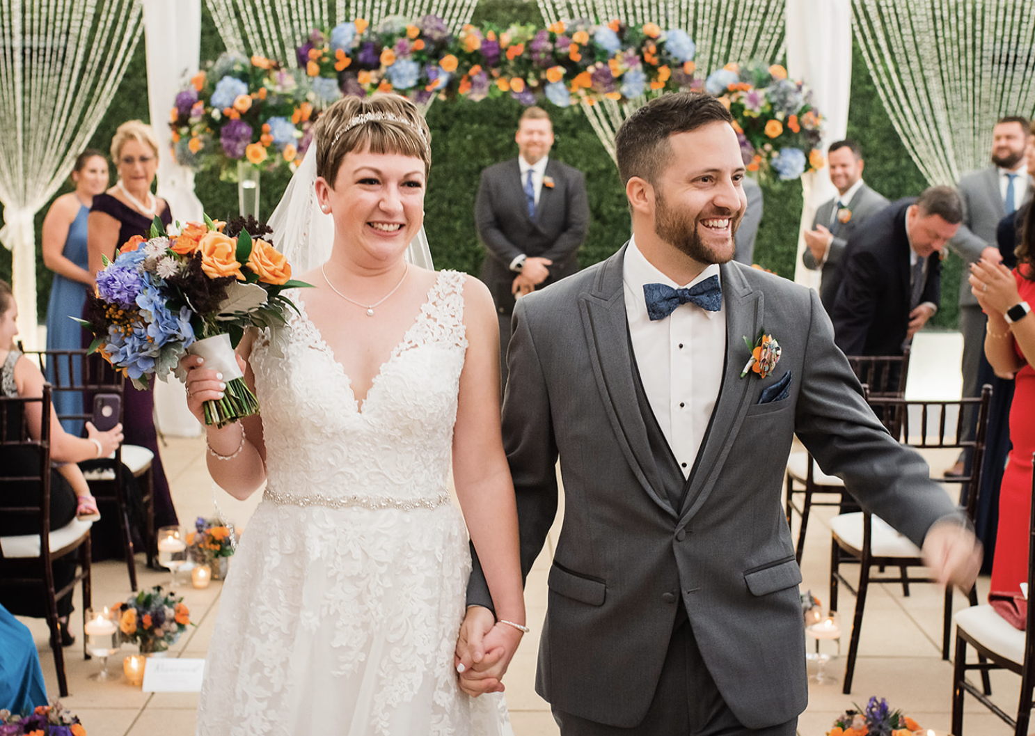 A smiling bride and groom walk down the aisle after a wedding ceremony in the Sam Houston Hotel Veranda