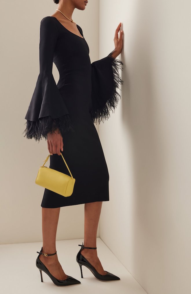 Black midi dress with yellow sleeves paired with a yellow purse.