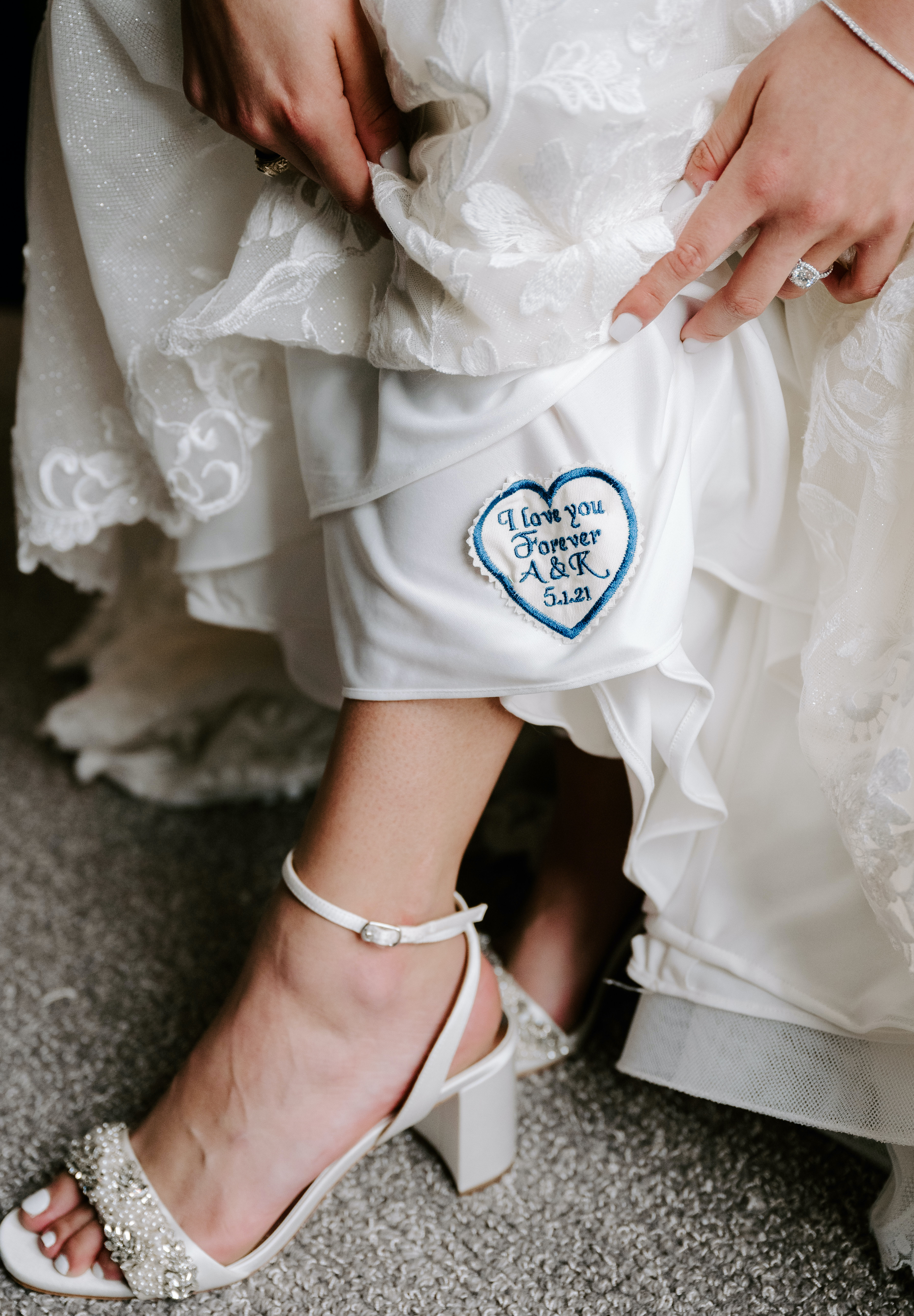 The bride has an blue embroidered heart on her wedding gown that says "I love you forever, A&K"