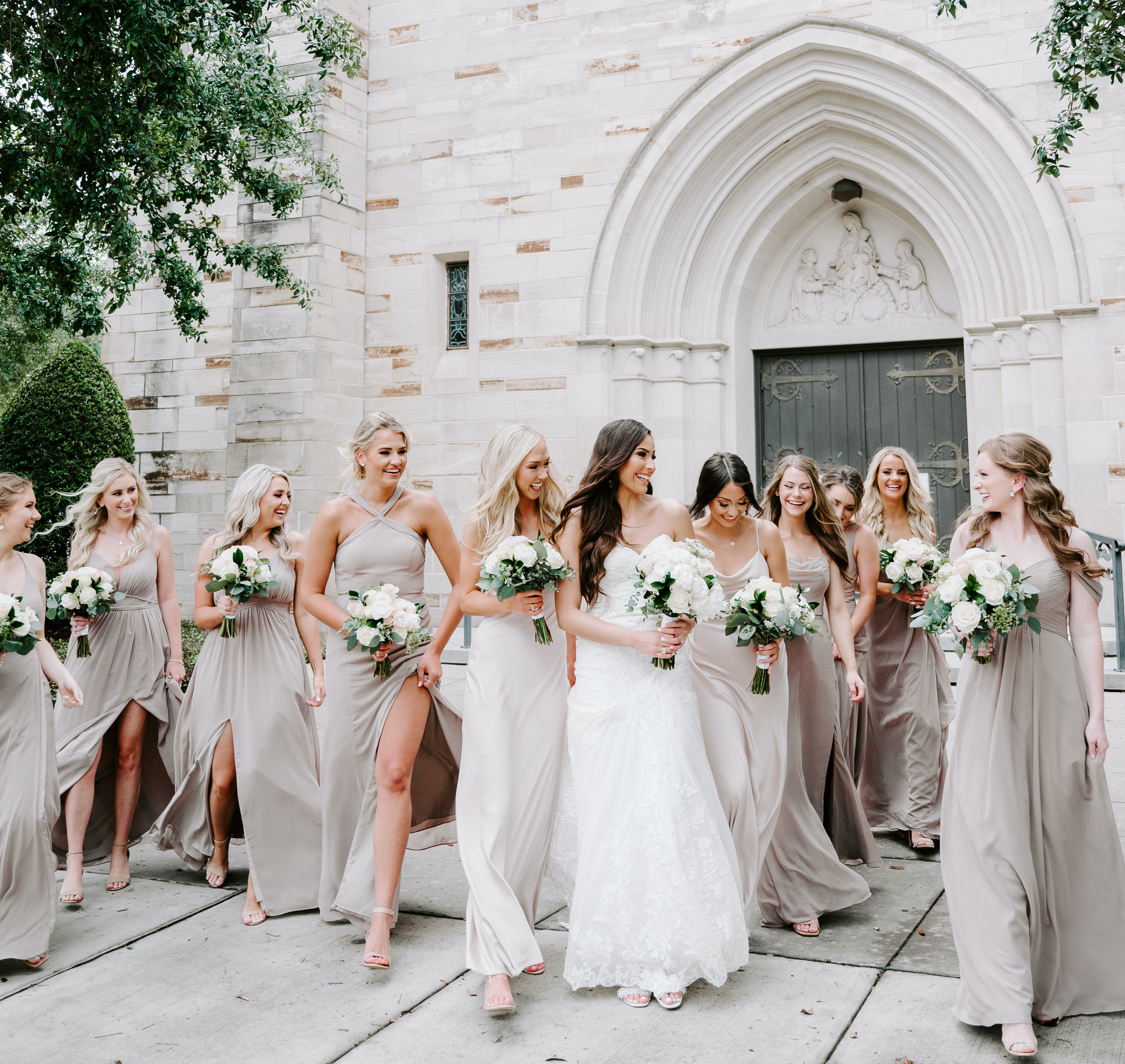 The bride and her bridesmaids are walking and laughing with one another.