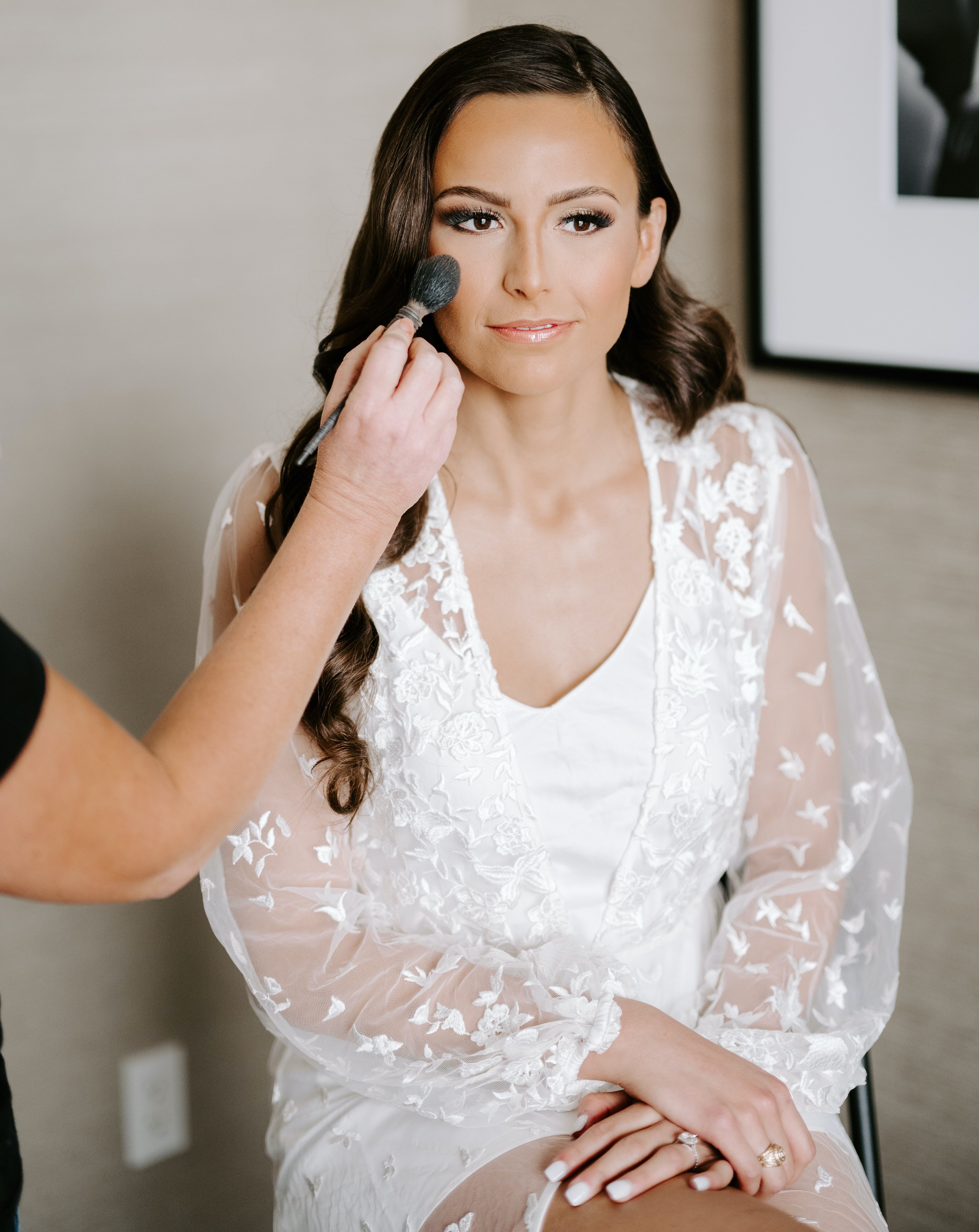 The bride is getting her makeup done for her elegant rainy wedding day.