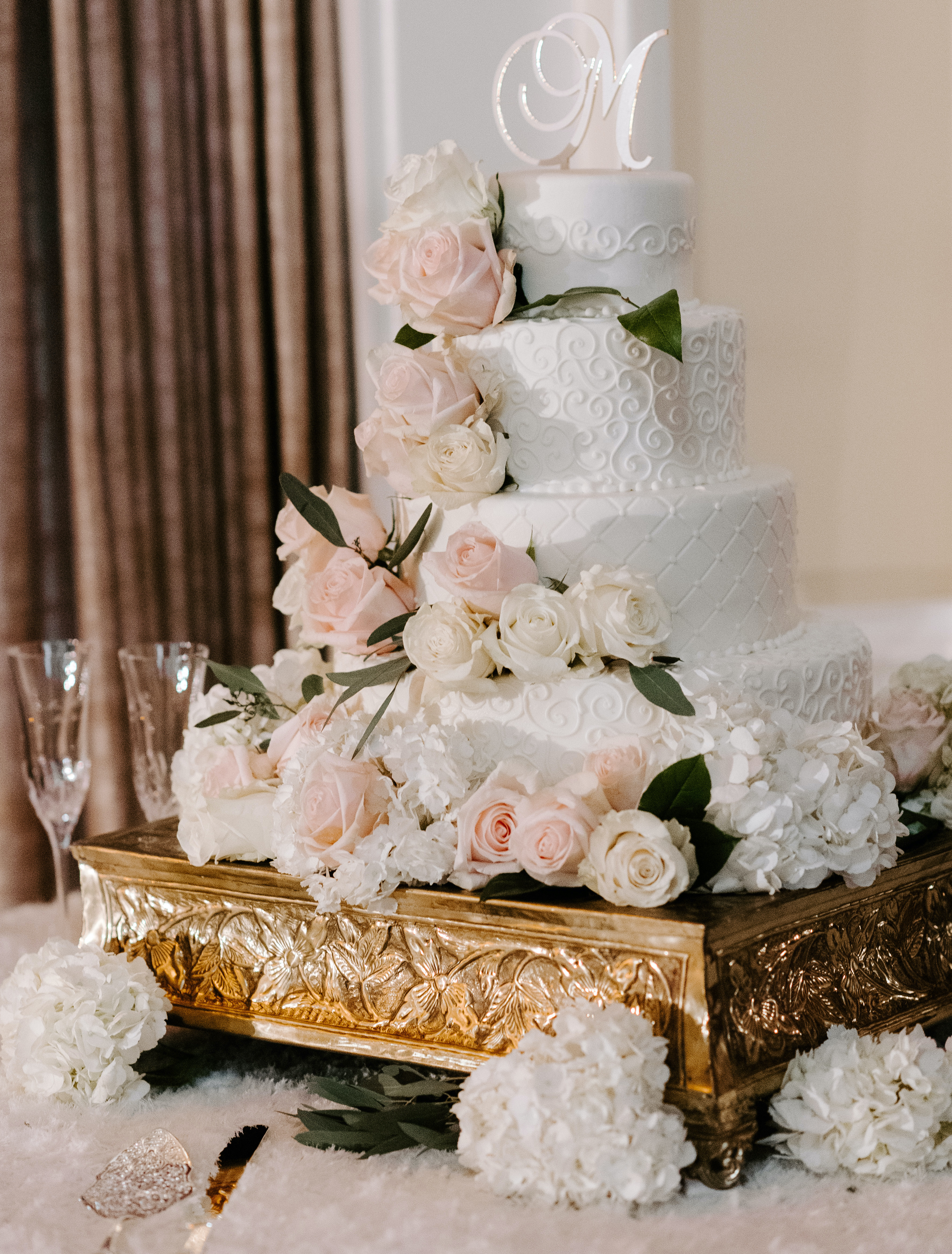 The white wedding cake with blush and ivory roses decorated on it.