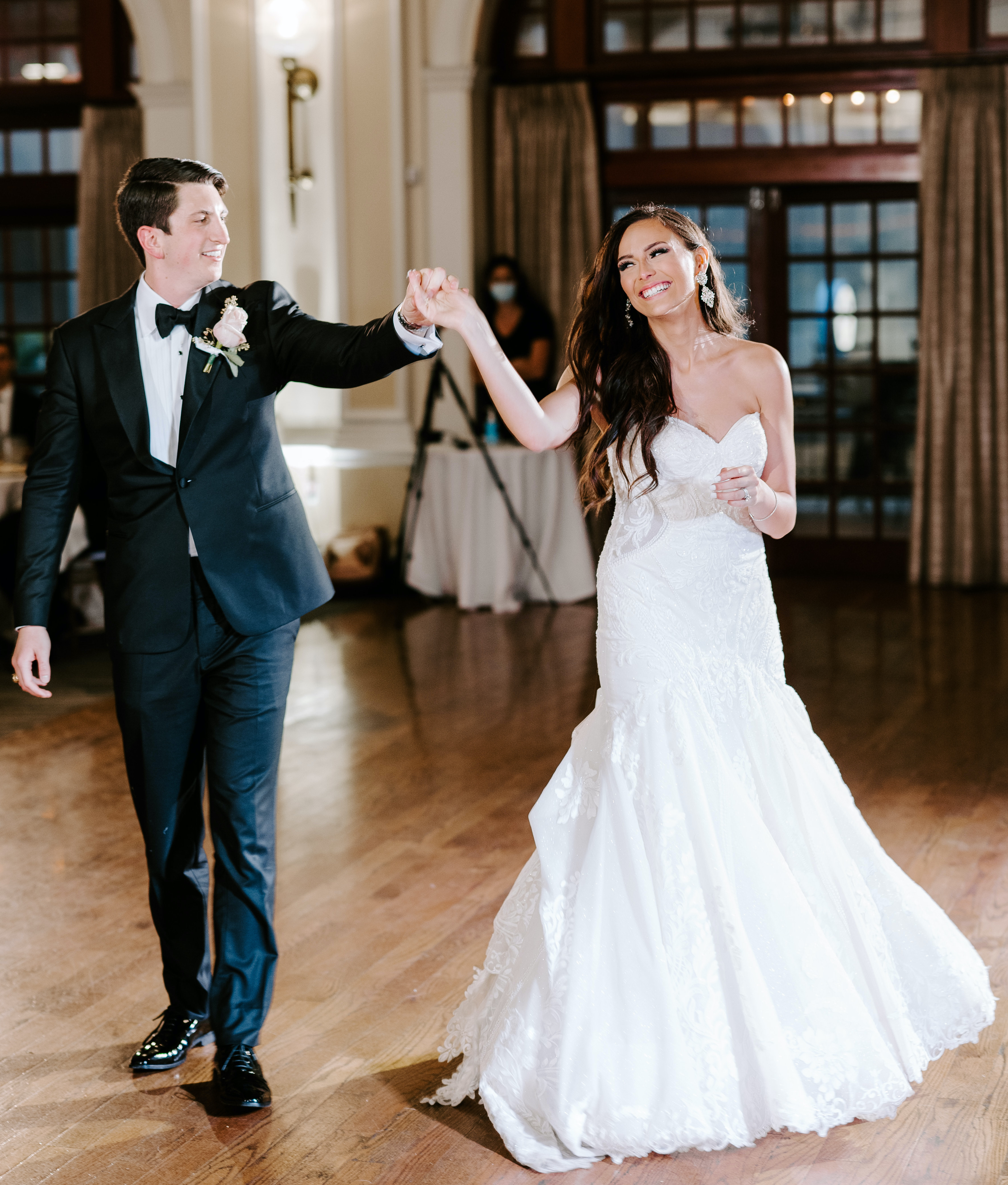 The groom twirls his bride during the first dance of the elegant rainy wedding.