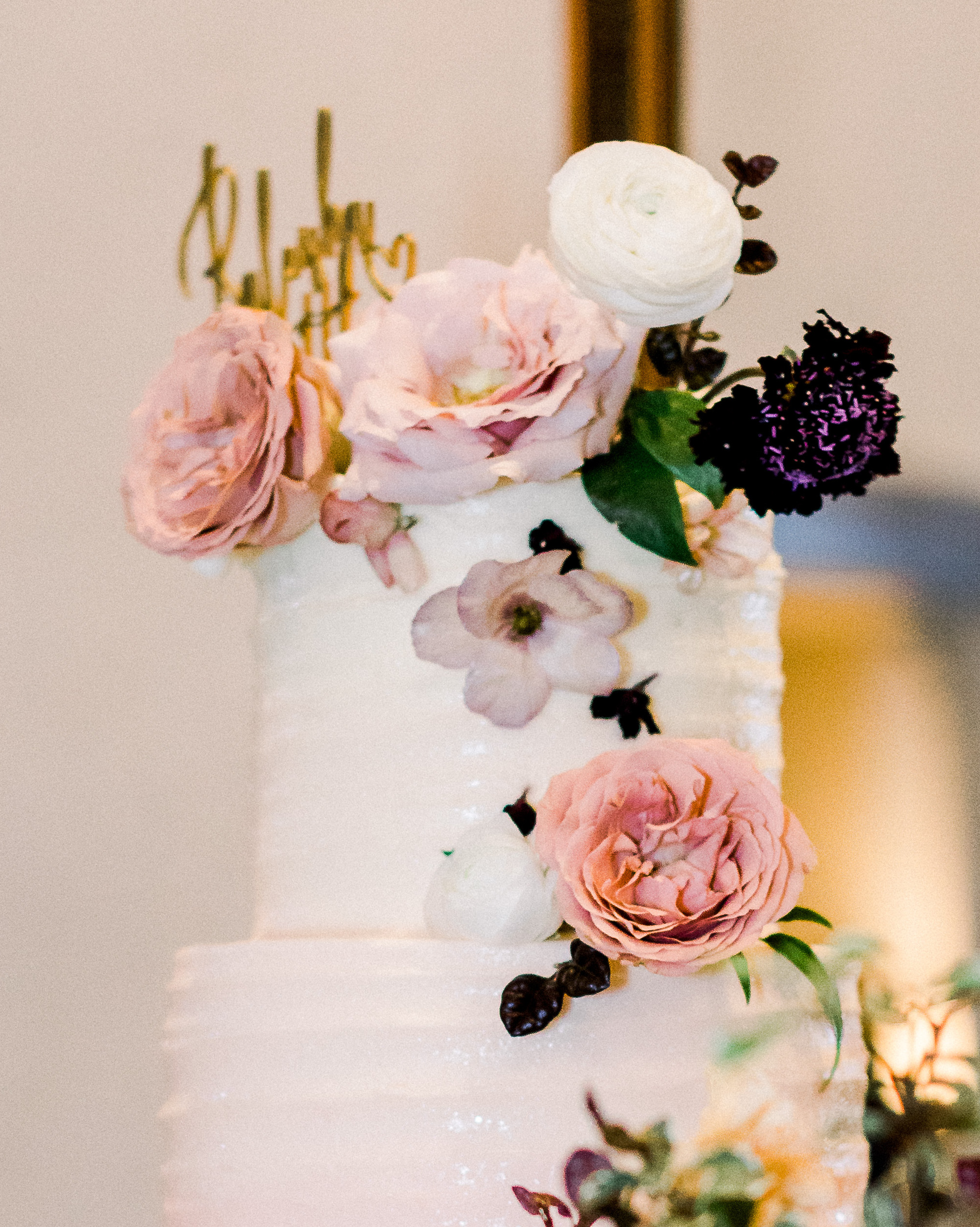 Ombre blush pink cake by Sweet Treets Bakery, topped with gold cake topper that reads, "Raleisha and Matthew" at a wedding reception in Dripping Springs, Texas. 