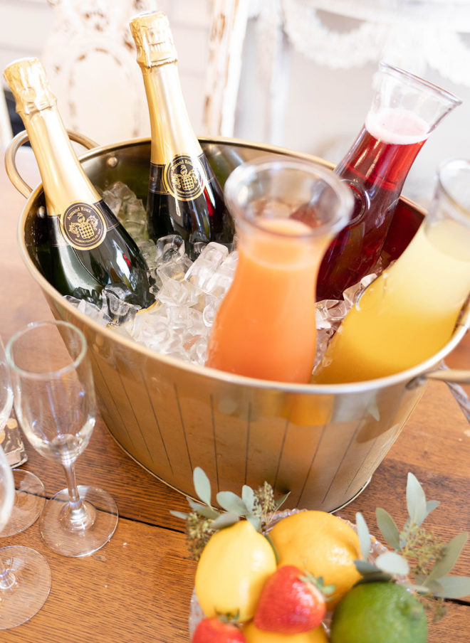 Champagne bottles, three glass jars of juice in an ice bucket with fresh fruit and champagne glasses in a guest suite at The Kendall Hill Country Inn in Boerne, Texas. 