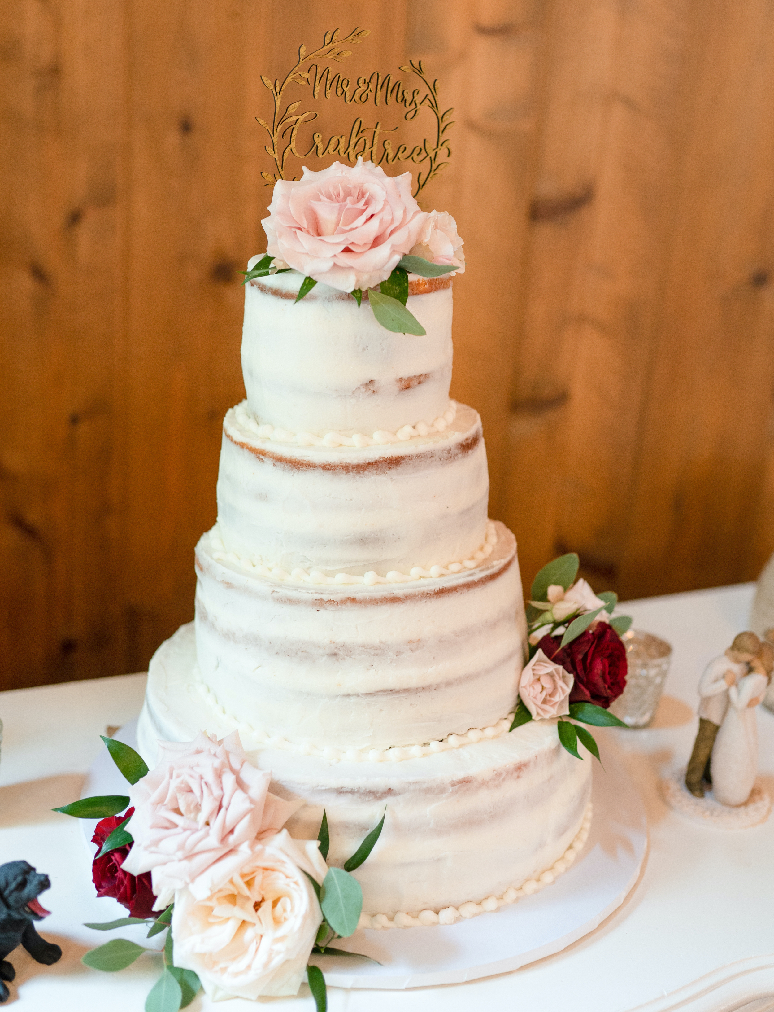 The bride and groom's wedding cake with white frosting and burgundy and blush flowers.