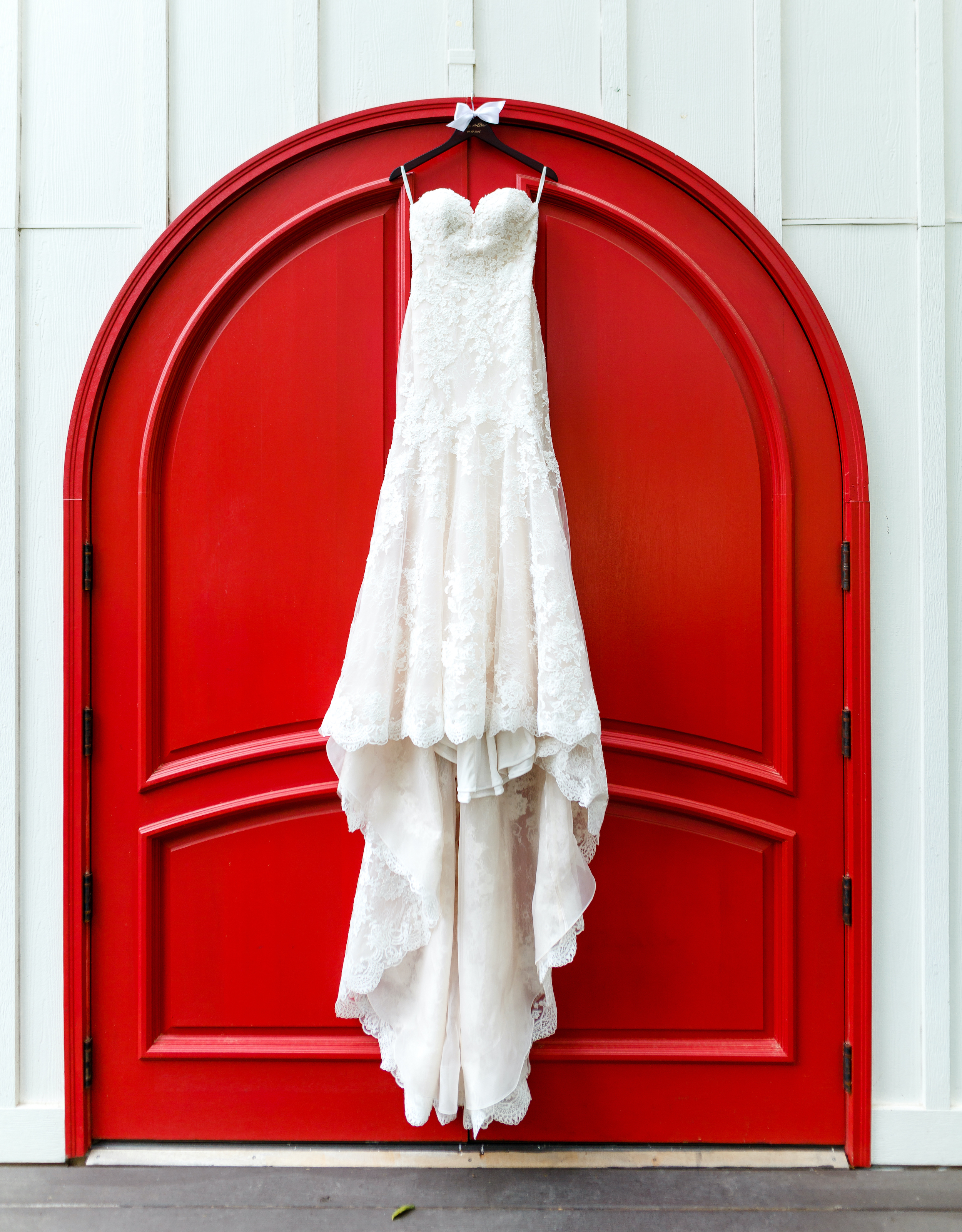 The bride's wedding gown hangs from a vibrant red door at The Carriage House.
