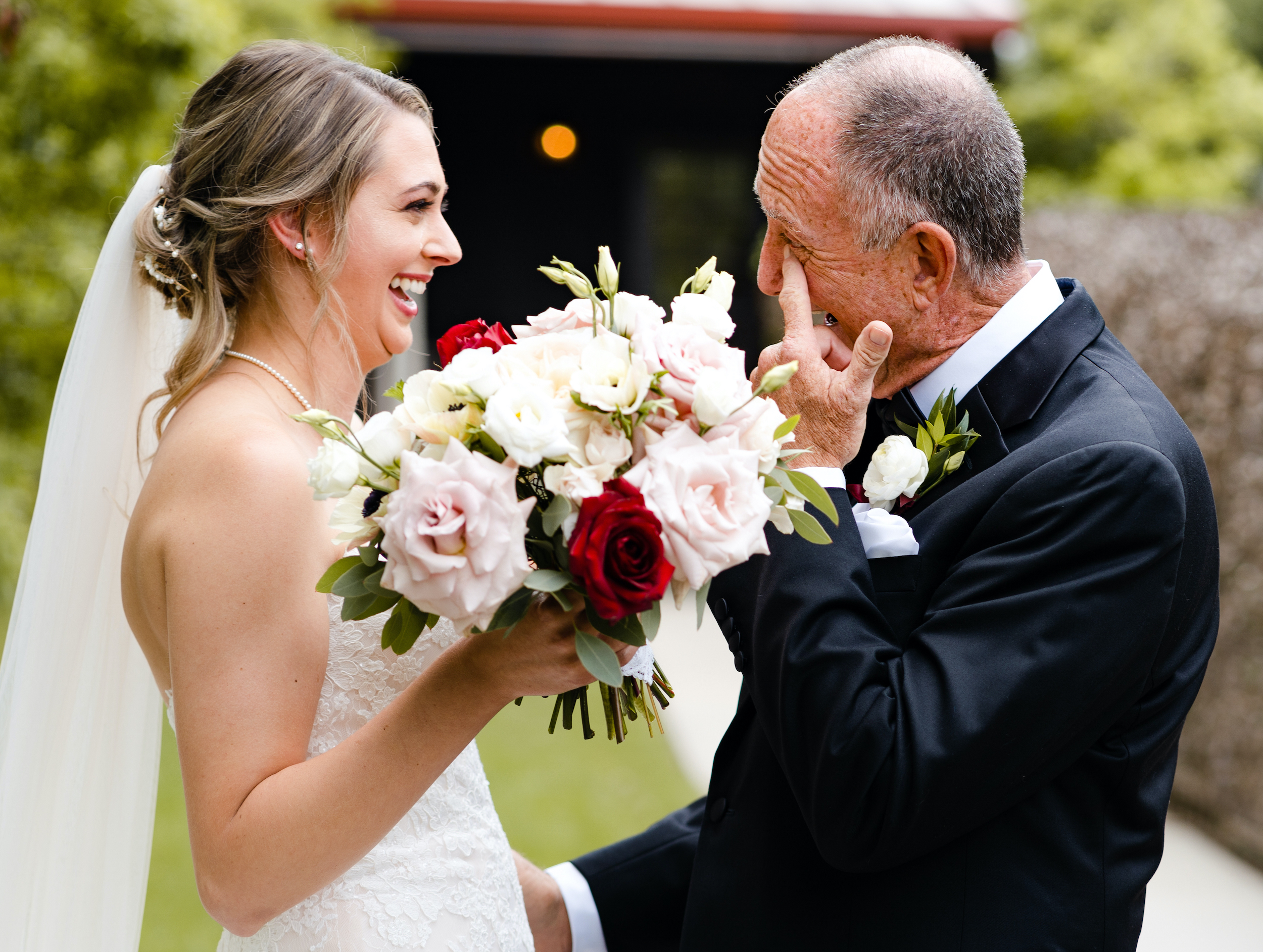 The bride does her first look with her father, who wipes a tear from his eyes as he smiles.