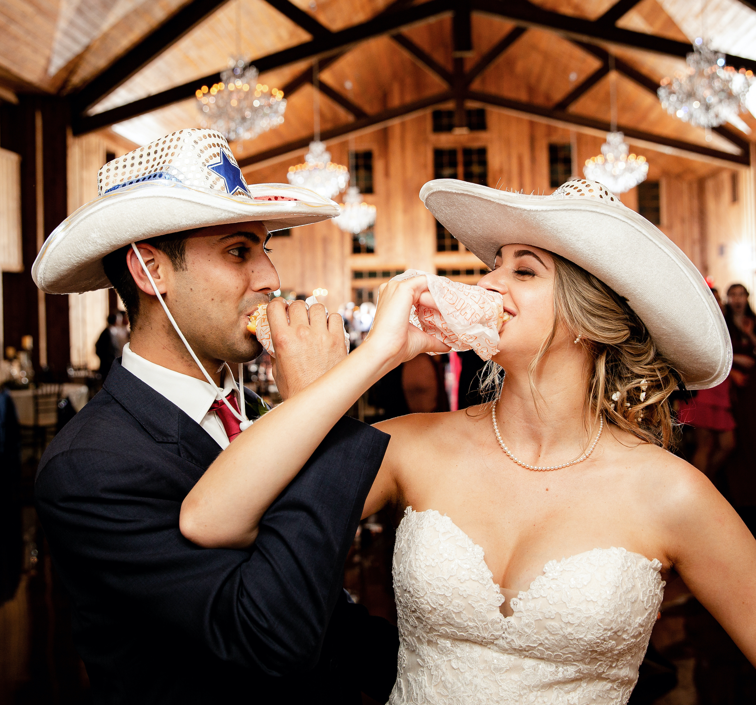 The bride and groom smile while eating Whataburger sandwiches.